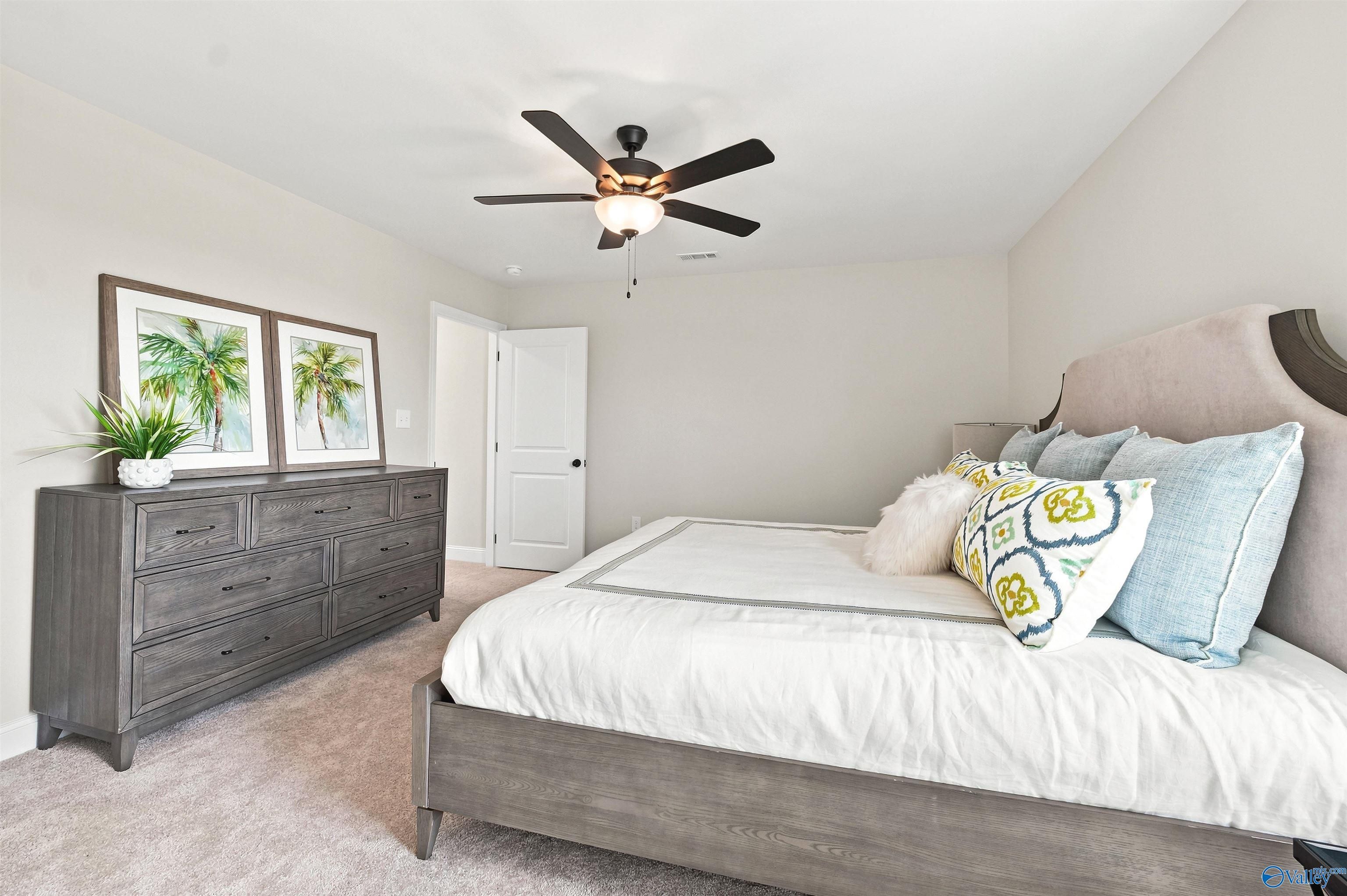 Spacious bedroom with modern gray furniture in The Burton B floor plan at Heritage Lakes in New Market, Alabama.