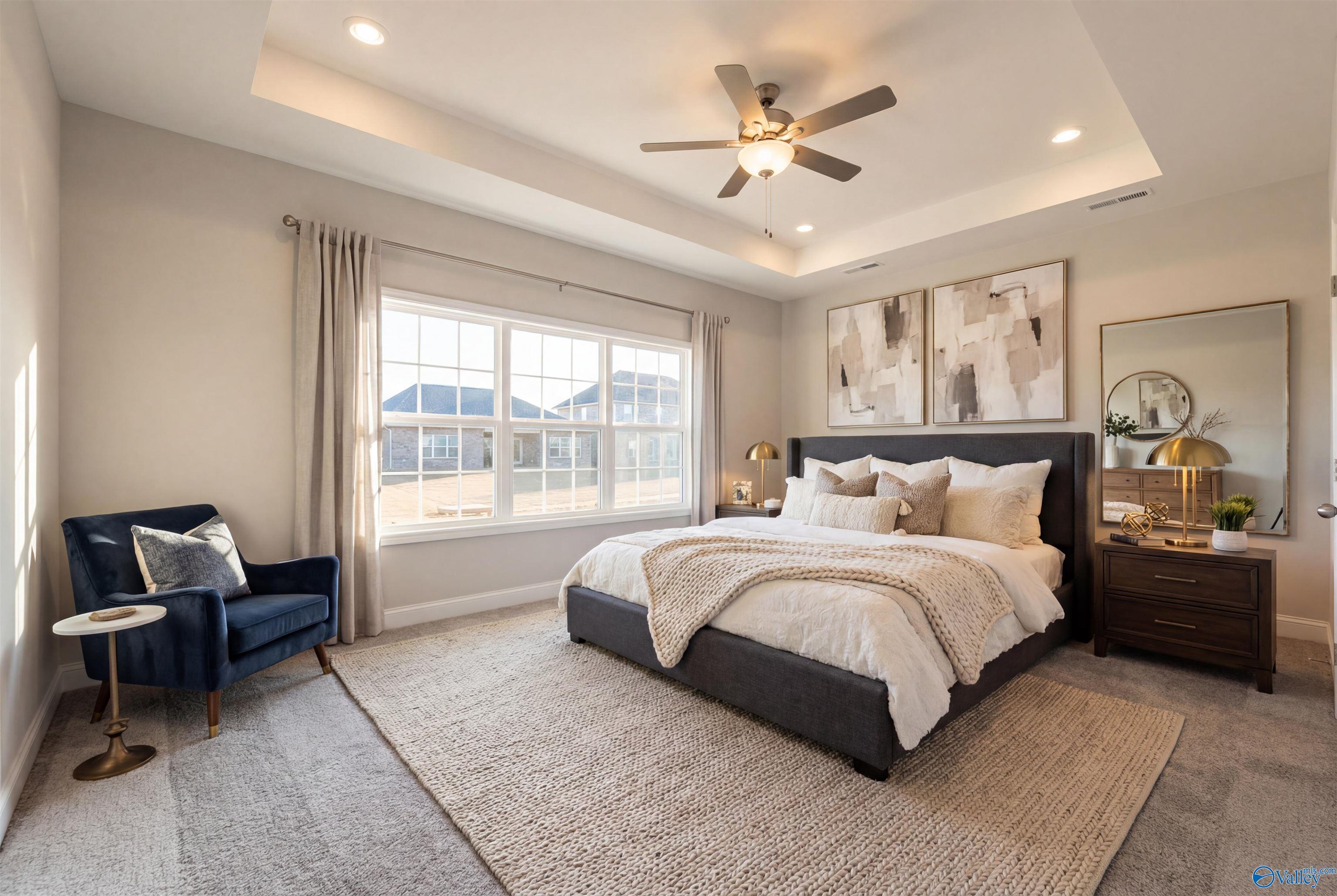 Elegant master bedroom with king bed, tray ceiling, ceiling fan, and large windows in Davidson Homes The Montgomery B, Toney, Alabama