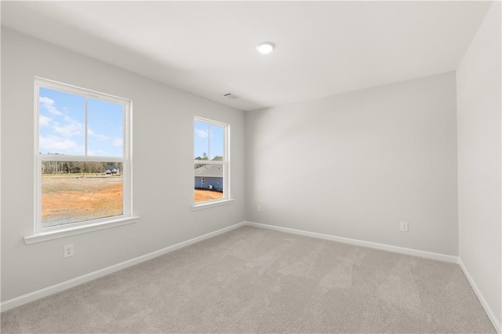 Spacious bedroom with large windows overlooking fields and construction in Davidson Homes The Hickory B, Winder, Georgia