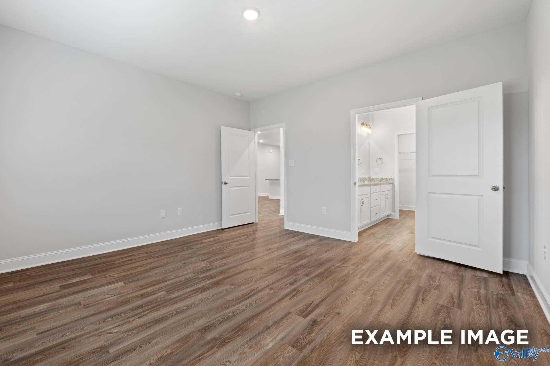 Spacious bedroom with attached bath, hardwood floors, neutral gray walls in Davidson Homes The Cumberland, Decatur Alabama