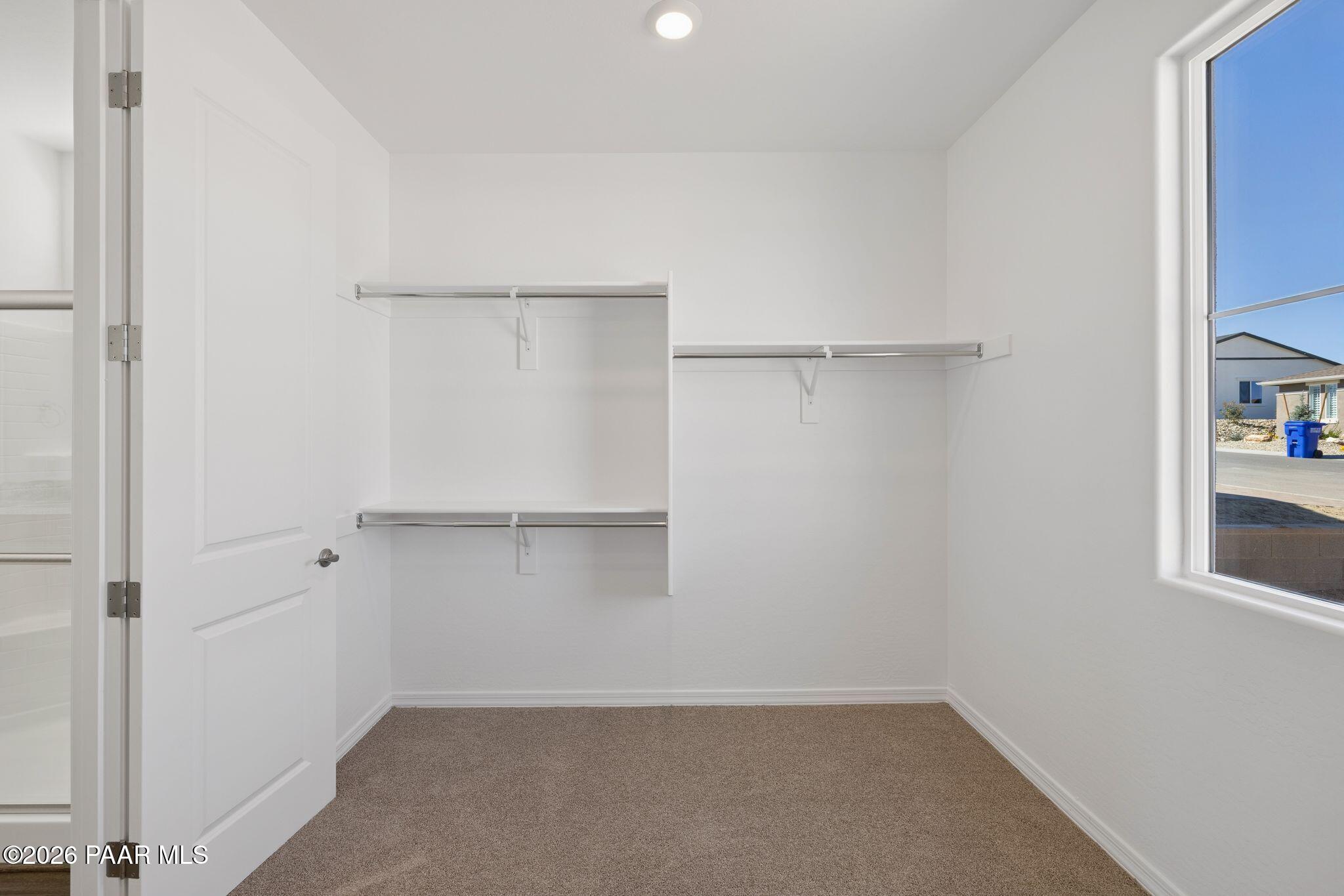 Spacious walk-in closet with built-in white shelving and hanging rods in Davidson Homes The Monarch A, Prescott, AZ