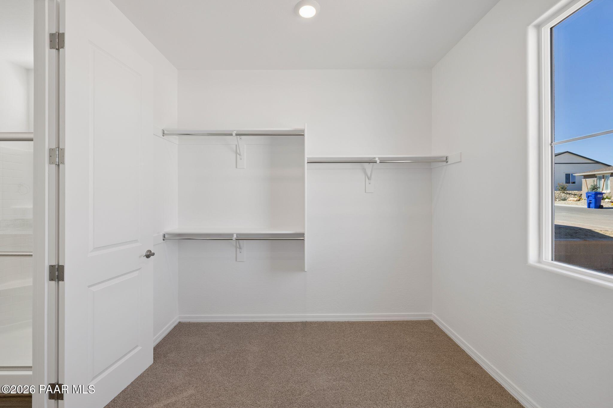 Spacious walk-in closet with built-in white shelving and hanging rods in Davidson Homes The Monarch A, Prescott, AZ