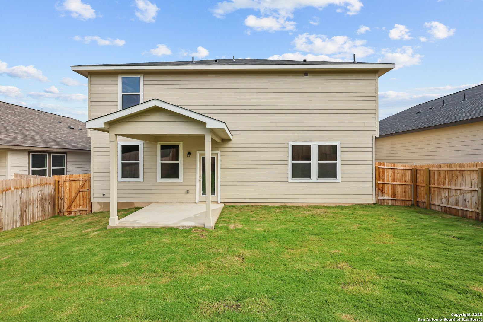 Covered back patio with large windows overlooking fenced green backyard in Davidson Homes The Douglas G, Royal Crest, San Antonio