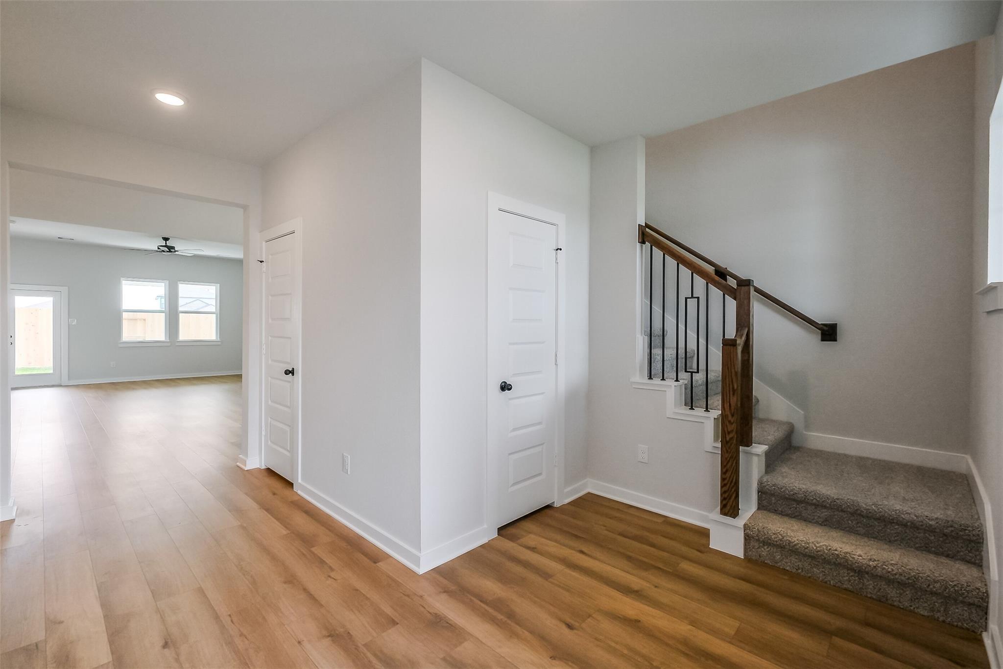 Bright entryway with wooden staircase, hardwood floors, and open hallway in Davidson Homes The Tierra B, Beasley, Texas