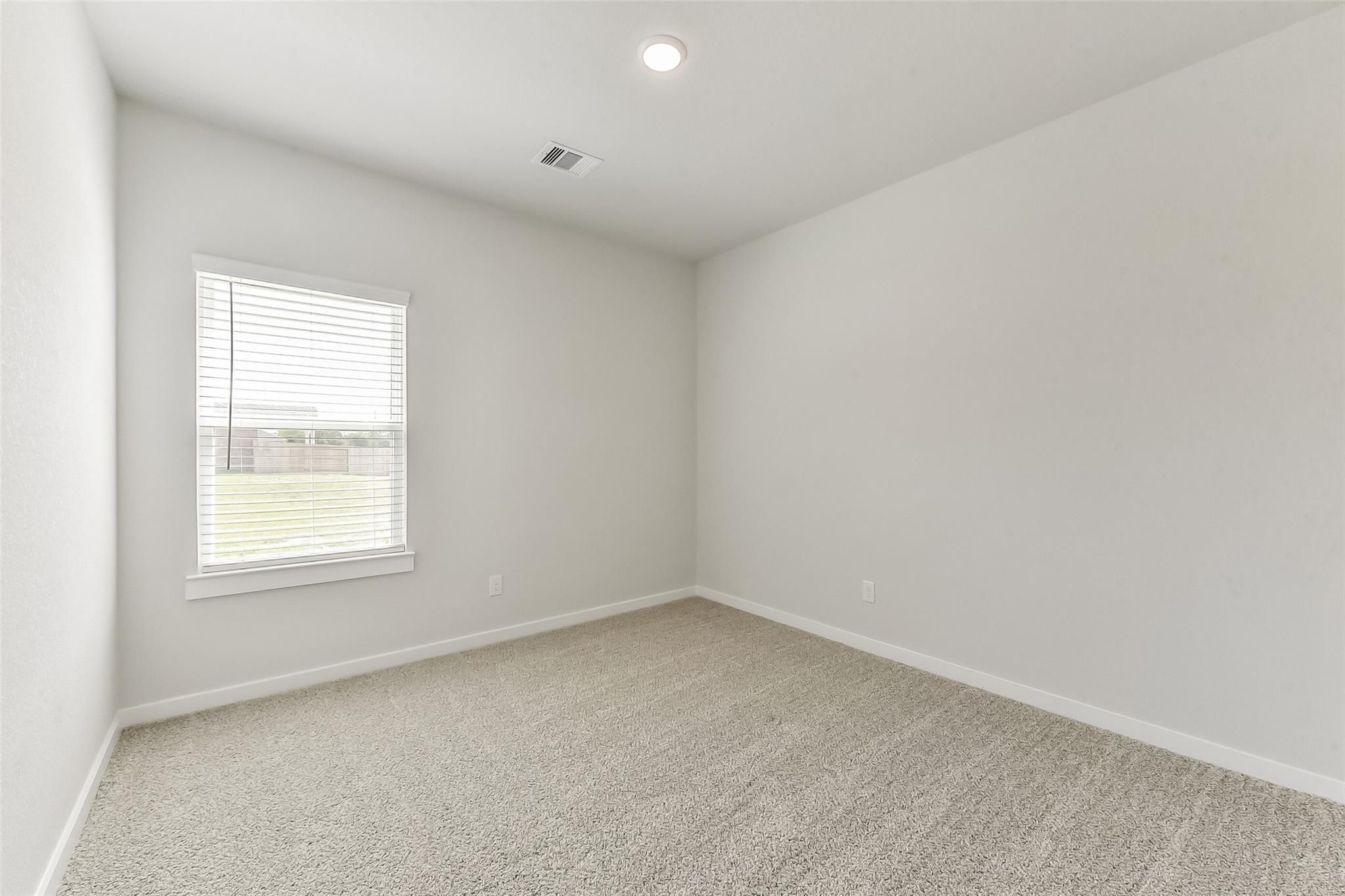 Empty bedroom with light gray walls, beige carpet, window blinds, and natural light in Davidson Homes The Frio G, Magnolia, Texas