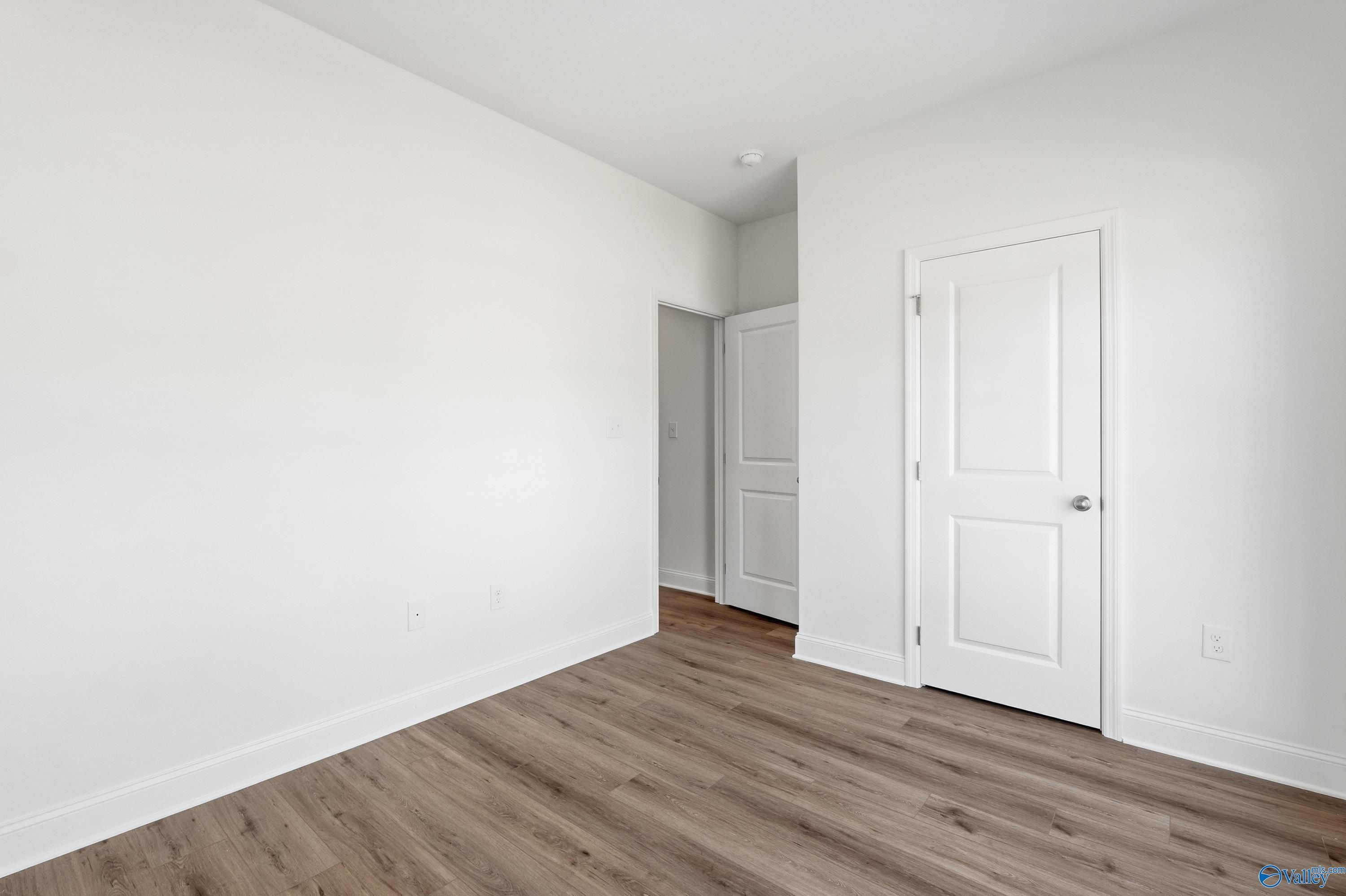 Bright bedroom with luxury vinyl plank flooring and white interior doors in The Asheville floor plan, Jaguar Hills.