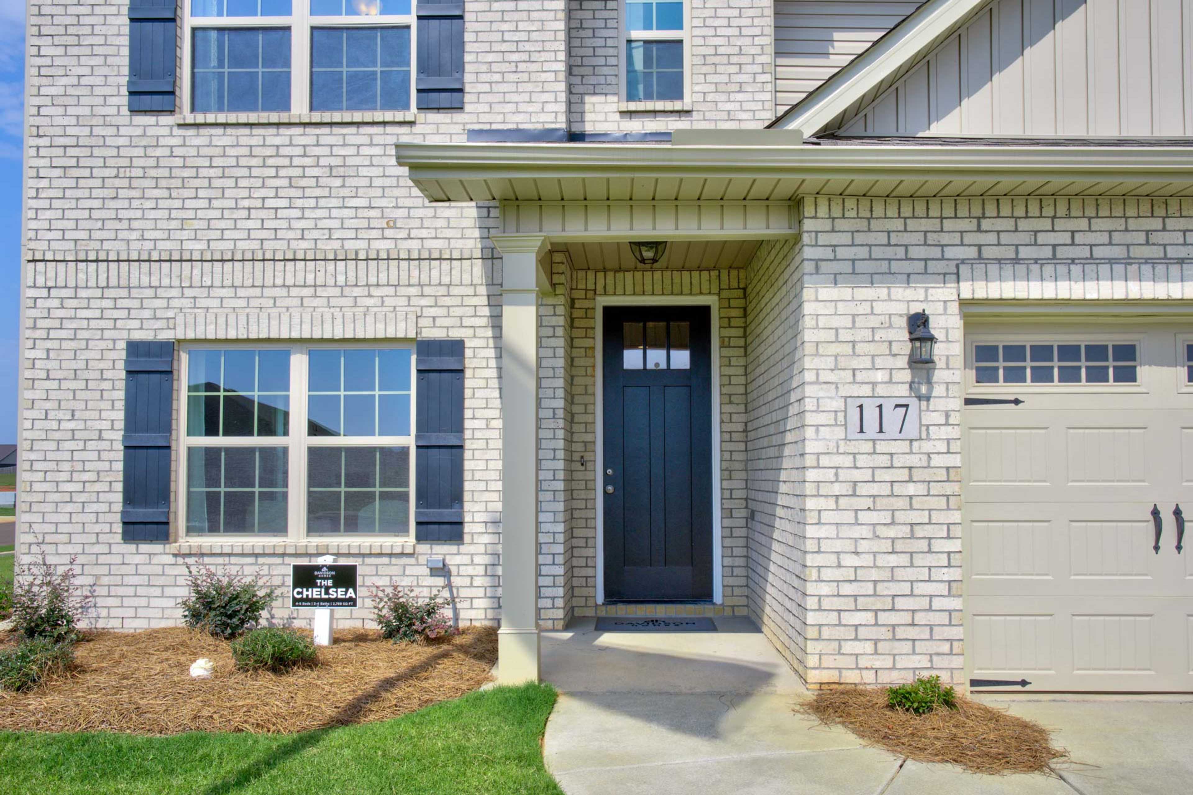 Brick home exterior at Walker's Hill in Meridianville Alabama with blue shutters, dark door, and garage