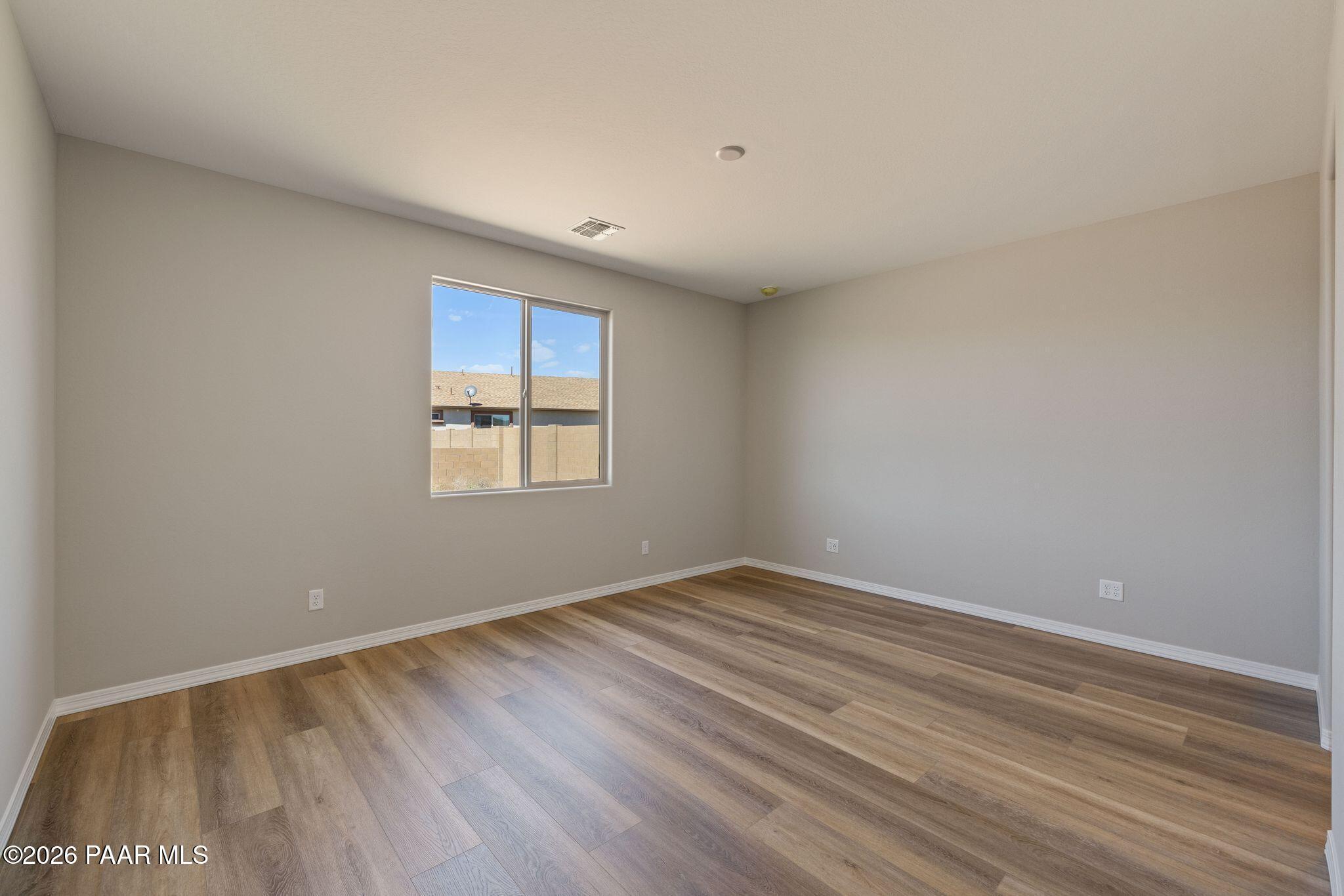 Bright secondary bedroom with luxury vinyl plank flooring and large window in Davidson Homes The Frontier A, Prescott Valley, AZ