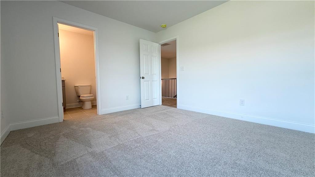 Spacious carpeted bedroom with attached bathroom in The Hickory C floor plan at Wehunt Meadows, Hoschton, Georgia.