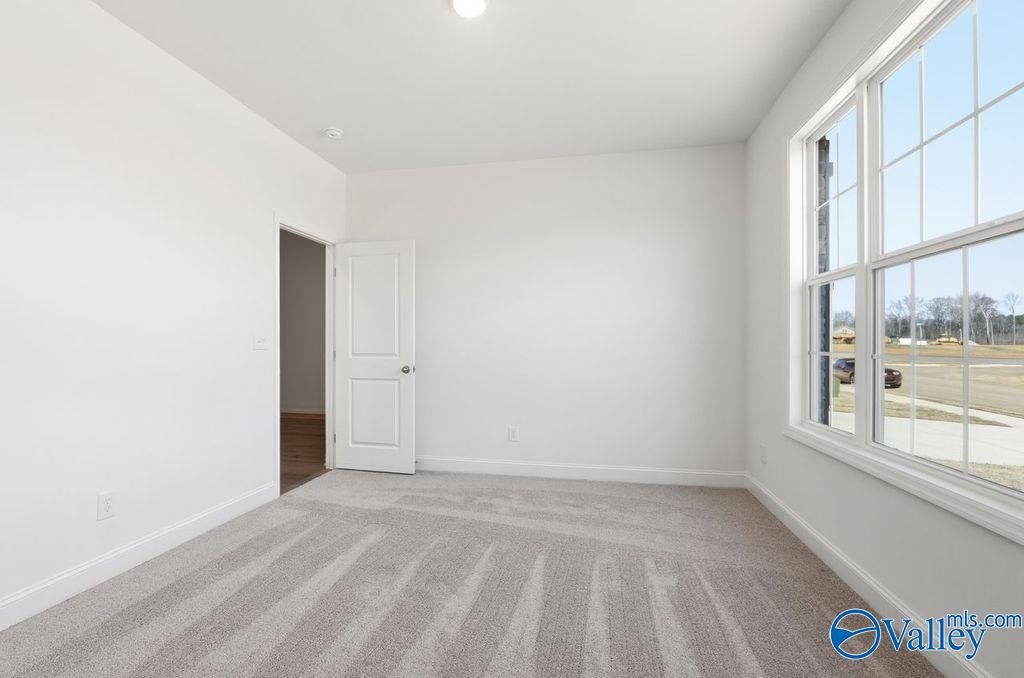 Bright secondary bedroom with white walls, berber carpet, open closet door, and large windows in The Montgomery, Hartselle, AL