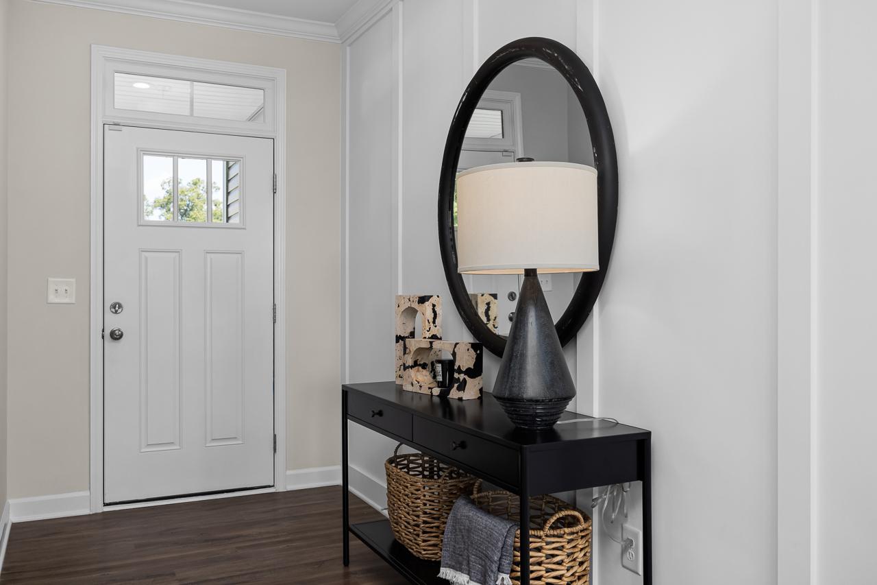 Elegant entryway at Wellers Knoll in Lillington NC with white front door, black console table, round mirror, lamp, and hardwood floors
