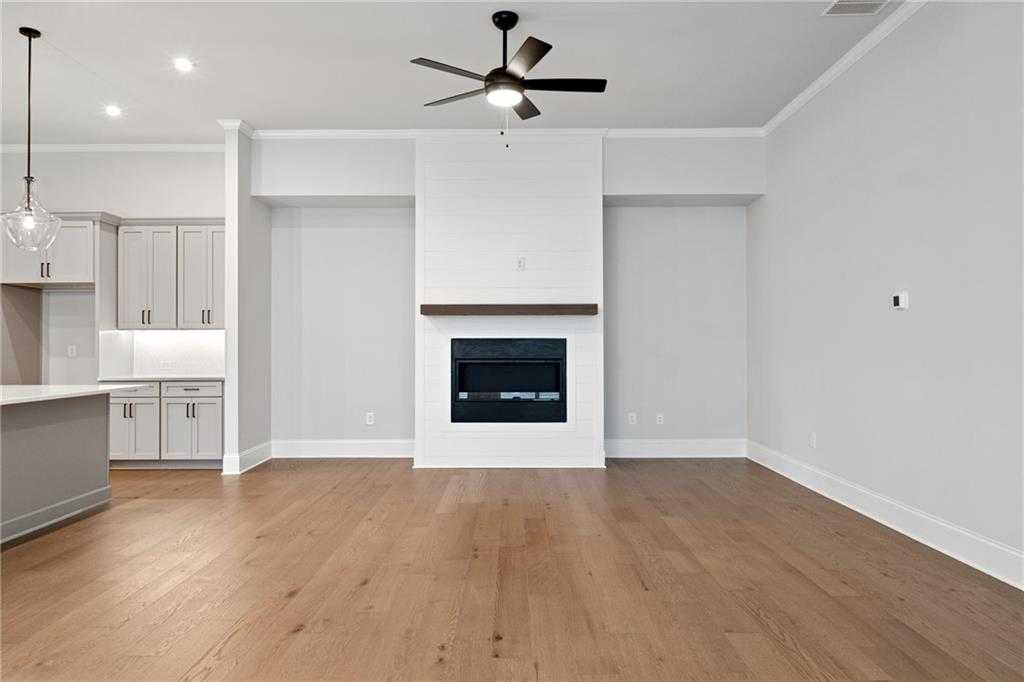 Cozy family room featuring modern white brick fireplace, hardwood floors, and ceiling fan in Davidson Homes The Seaside B, Woodstock, GA