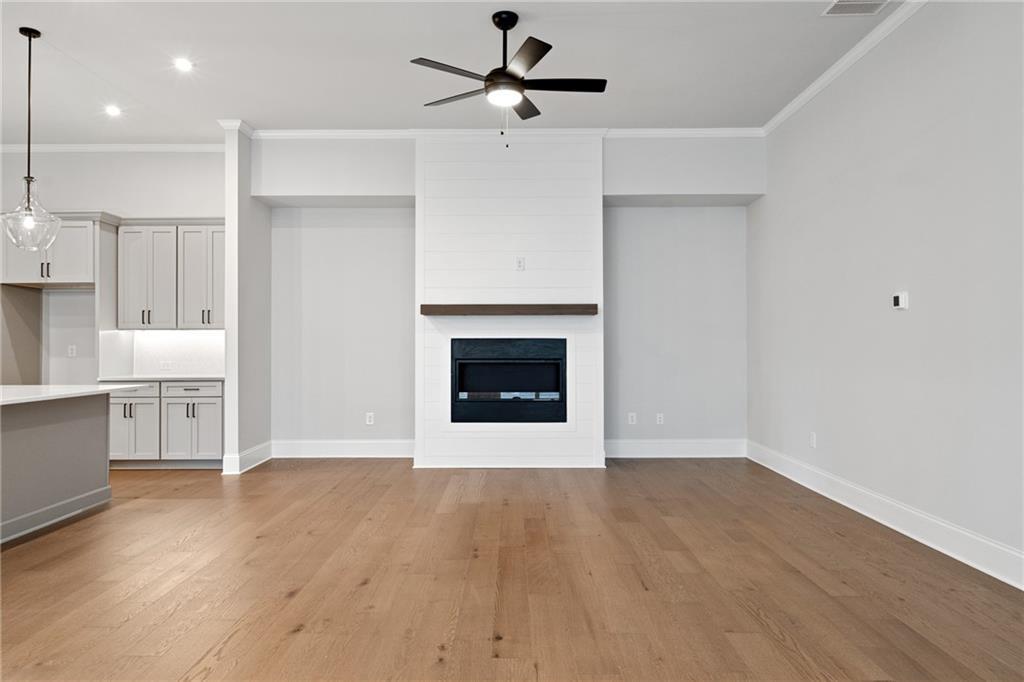 Cozy family room featuring modern white brick fireplace, hardwood floors, and ceiling fan in Davidson Homes The Seaside B, Woodstock, GA