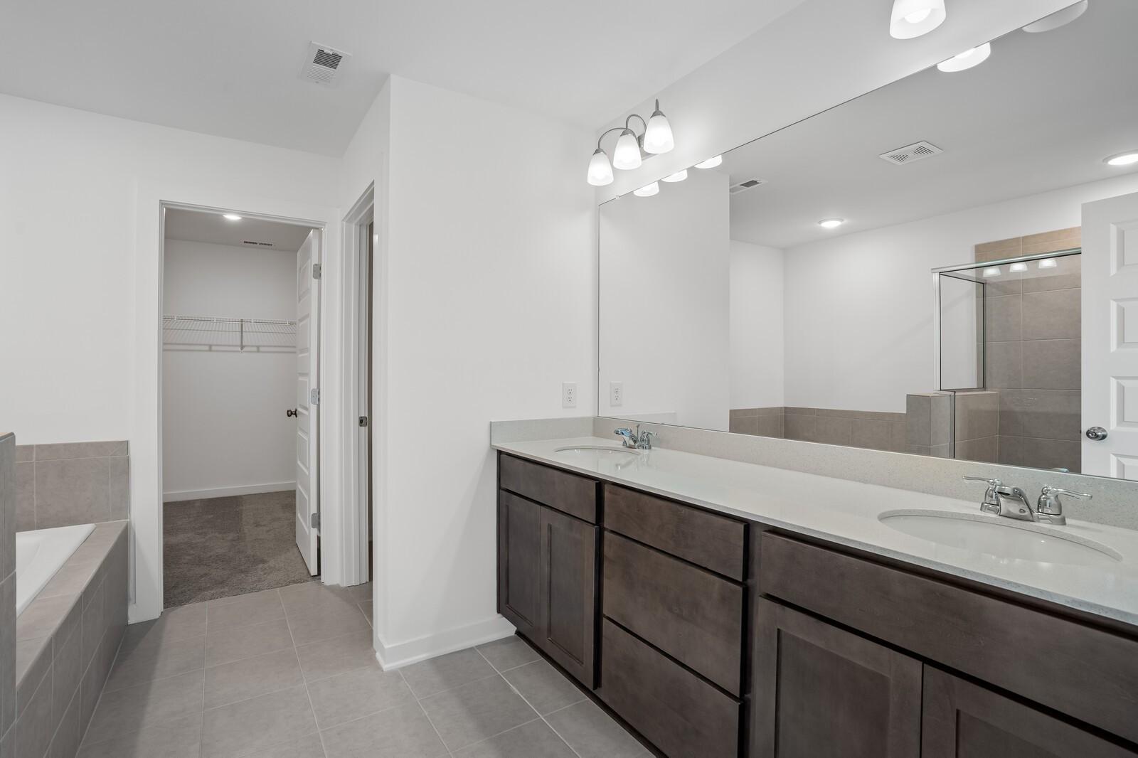Spacious master bathroom with double vanity, soaking tub, glass shower, and walk-in closet in Davidson Homes The Logan C, White House, TN