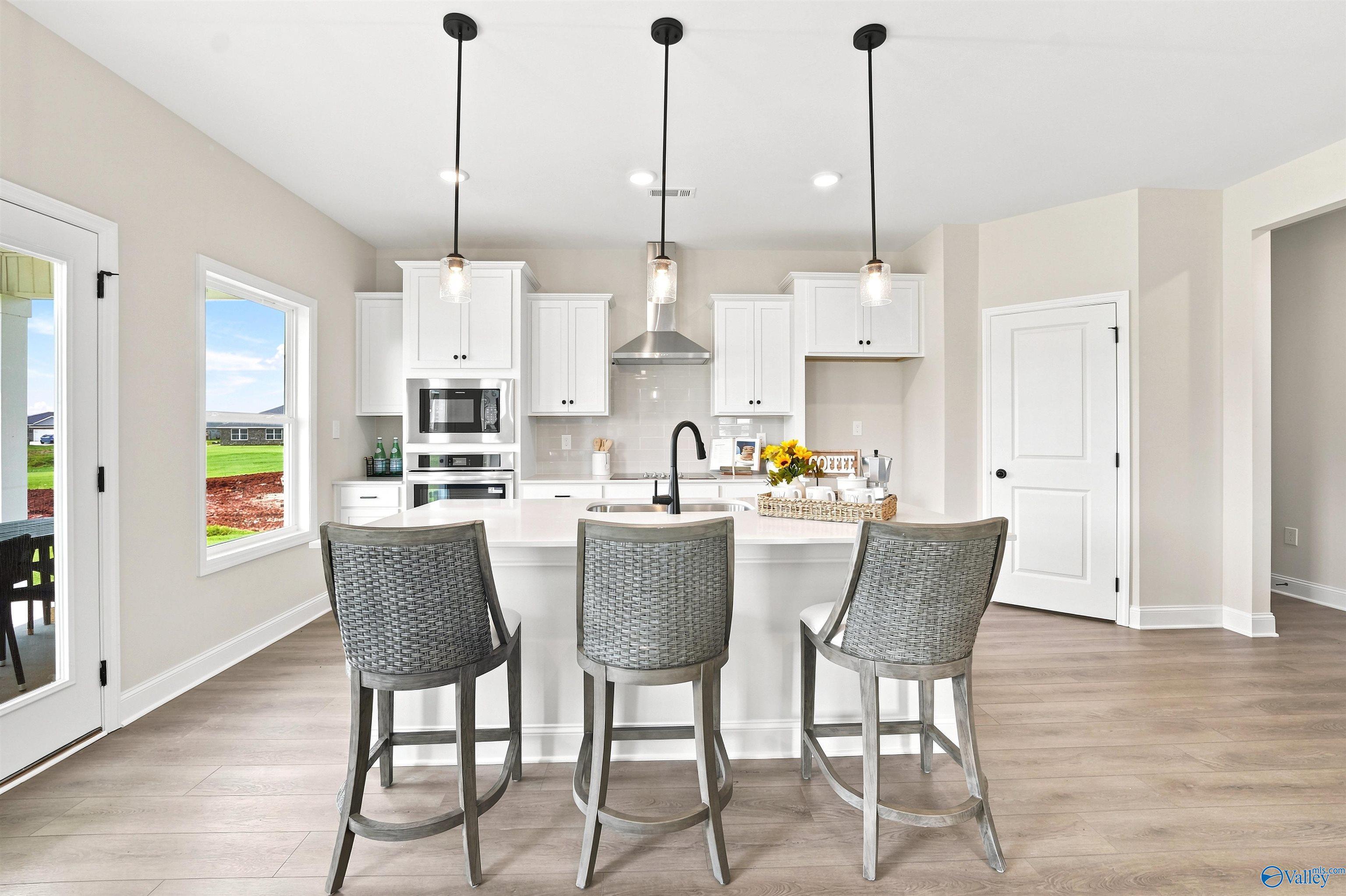 Modern kitchen with white cabinetry and island seating in The Burton B floor plan at Heritage Lakes, New Market, Alabama.
