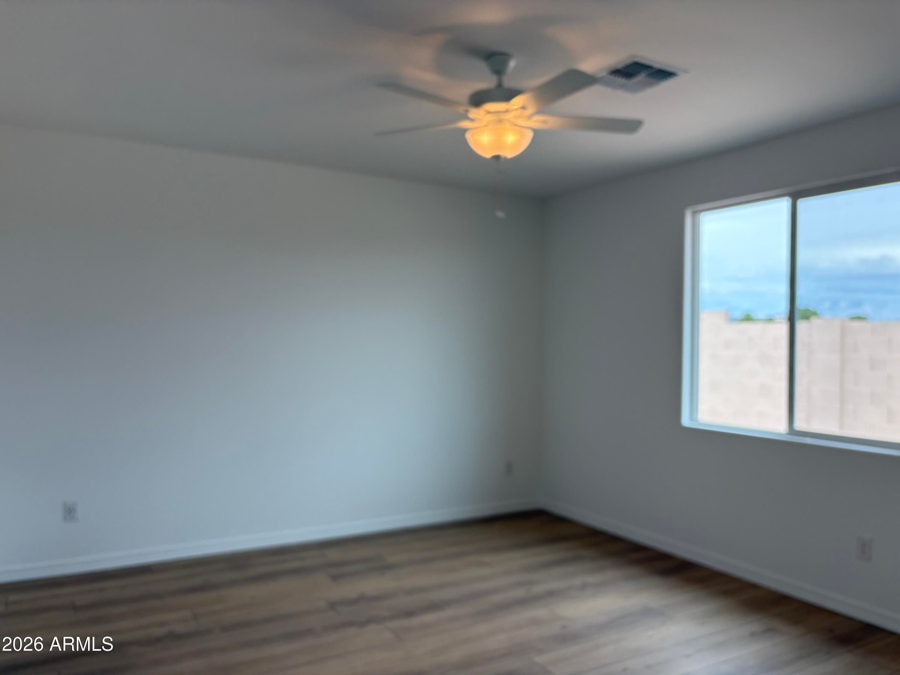 Bright bedroom with ceiling fan, wood-look flooring, and large window in Davidson Homes Evergreen B, Cottonwood, Arizona