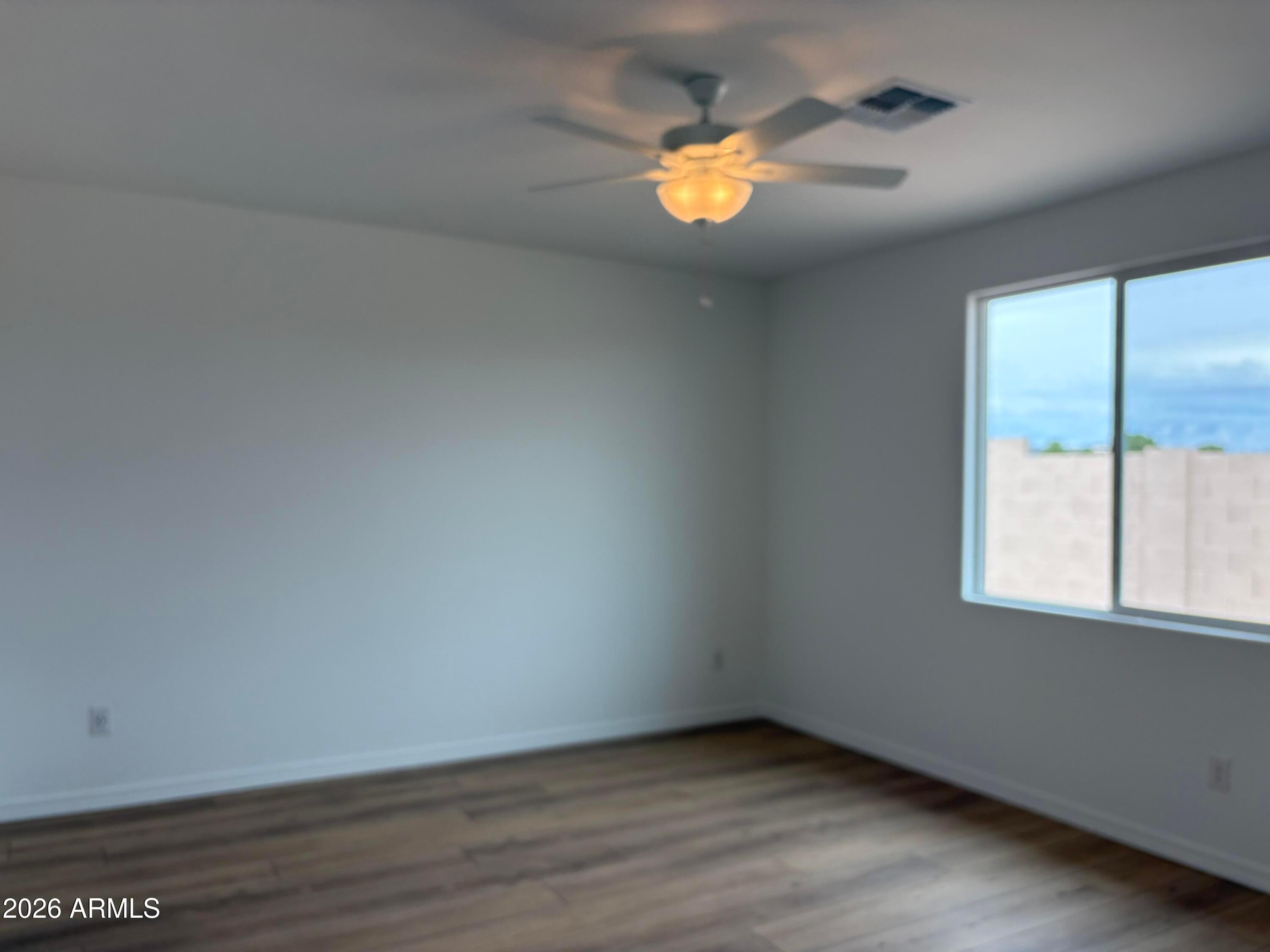 Bright bedroom with ceiling fan, wood-look flooring, and large window in Davidson Homes Evergreen B plan, Cottonwood, AZ