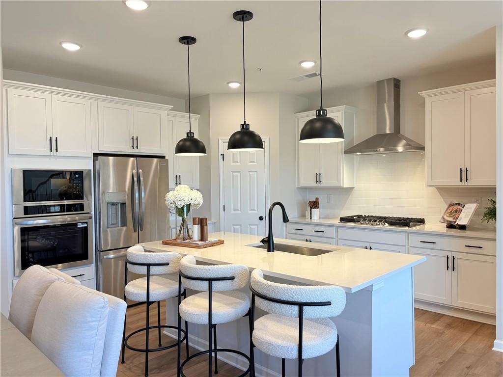 Modern white shaker kitchen island with stainless steel appliances and pendant lights in Davidson Homes The Durham D, Cumming, GA