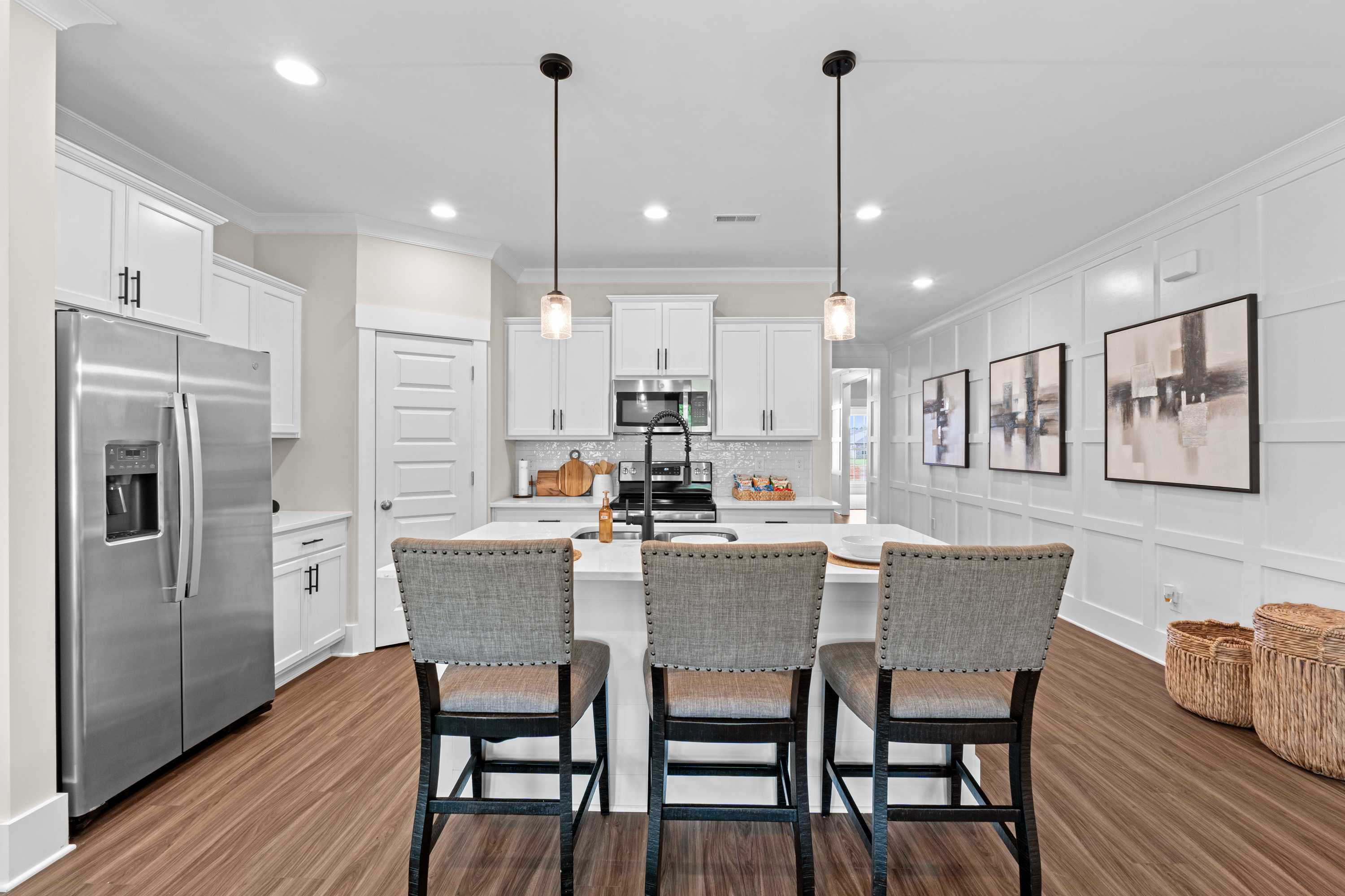 Spacious modern kitchen at Ivy Hills in Toney Alabama with white cabinets, large island, bar stools, hardwood floors