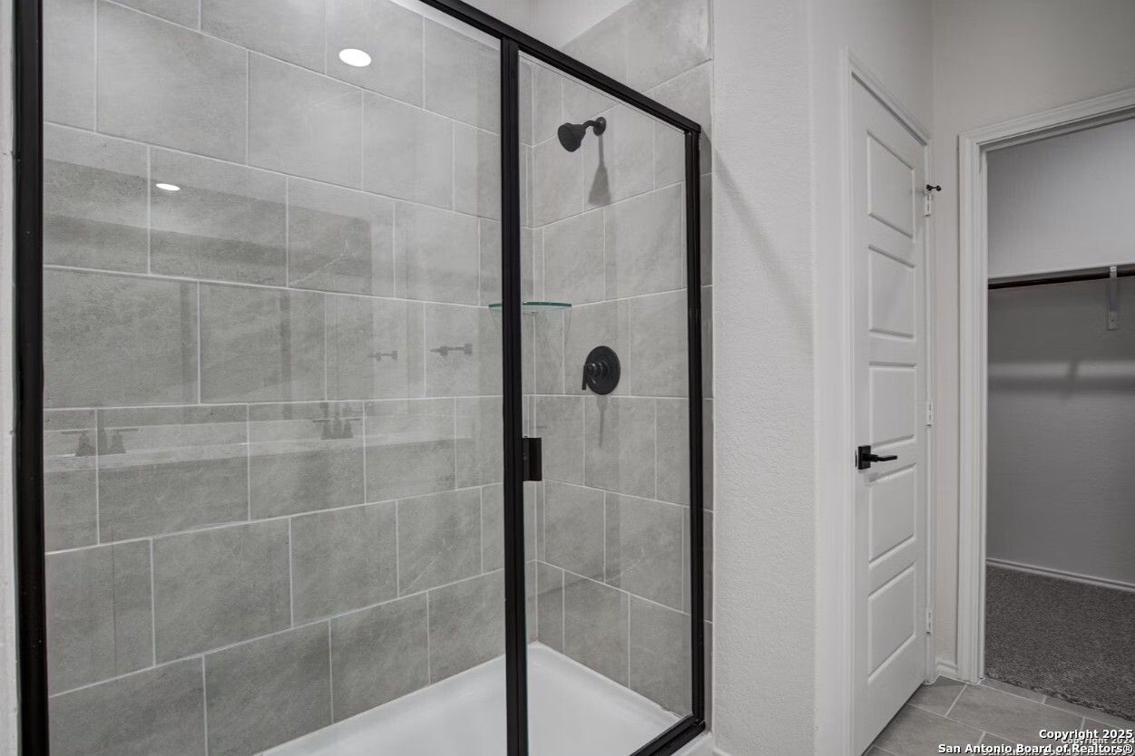 Frameless glass shower with gray subway tiles and matte black fixtures in master bath of Davidson Homes The Daphne H, Seguin, Texas