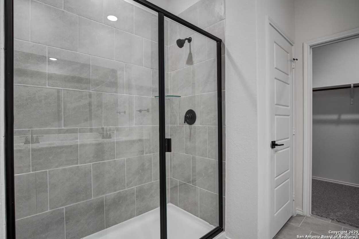 Frameless glass shower with gray subway tiles and matte black fixtures in master bath of Davidson Homes The Daphne H, Seguin, Texas