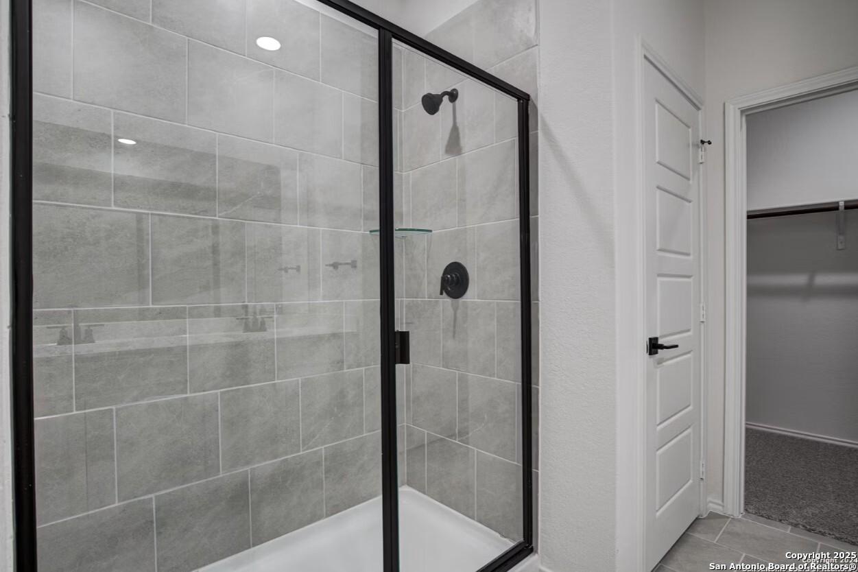 Frameless glass shower with gray subway tiles and matte black fixtures in master bath of Davidson Homes The Daphne H, Seguin, Texas
