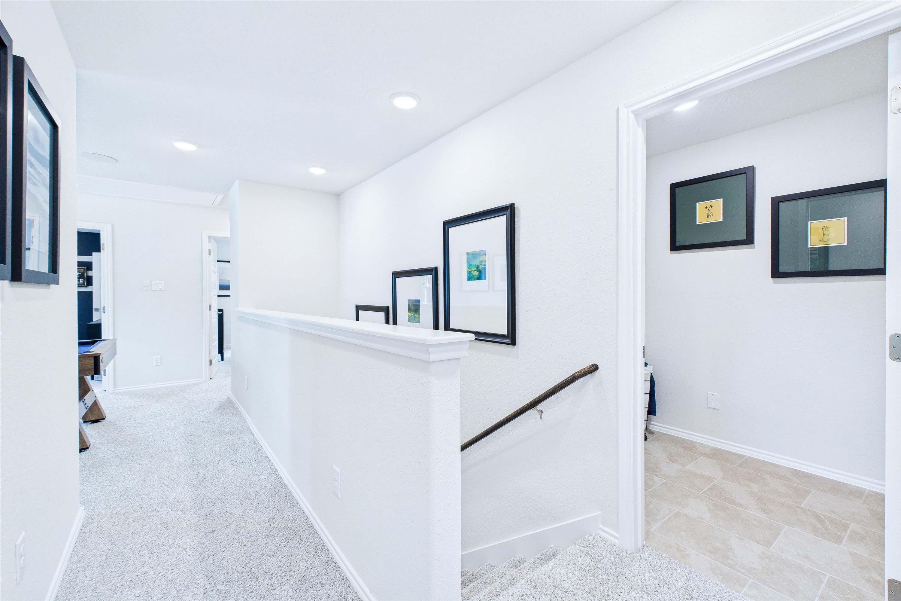 Bright upper-floor hallway in The Gillian C home design by Davidson Homes, featuring neutral carpet and gallery walls.