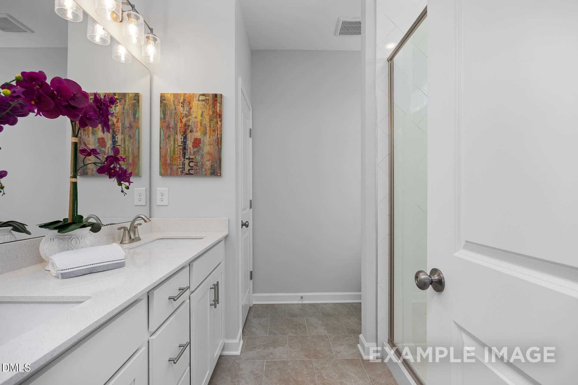Modern bathroom with white shaker vanity, frameless glass shower, and orchid decor in Davidson Homes The Carter C, Lillington, NC