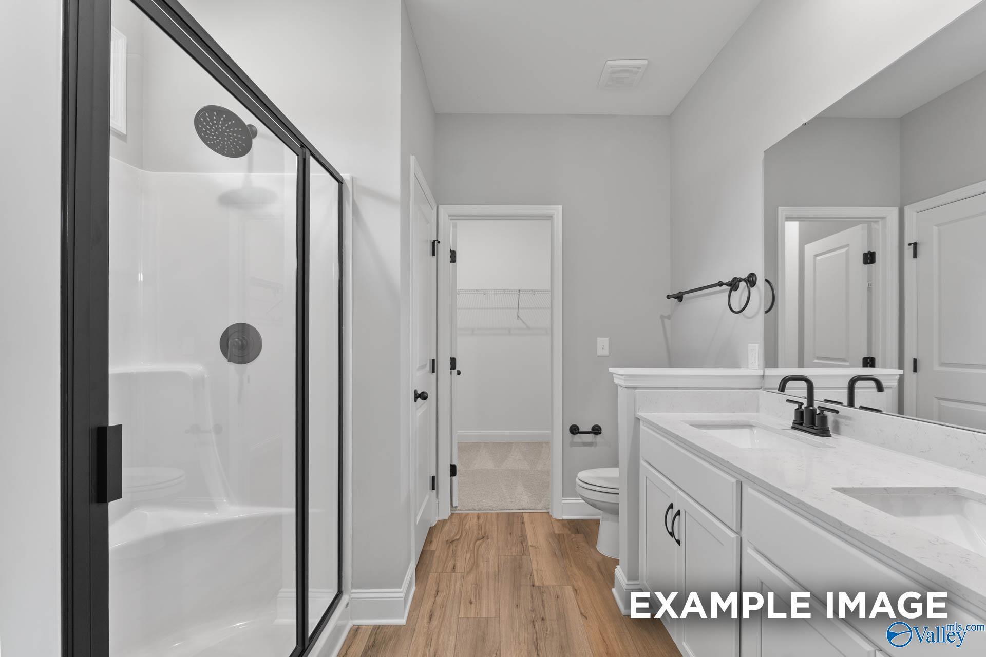 Modern primary bathroom with glass walk-in shower, double vanity, and black fixtures in Davidson Homes The Asheville C, Huntsville
