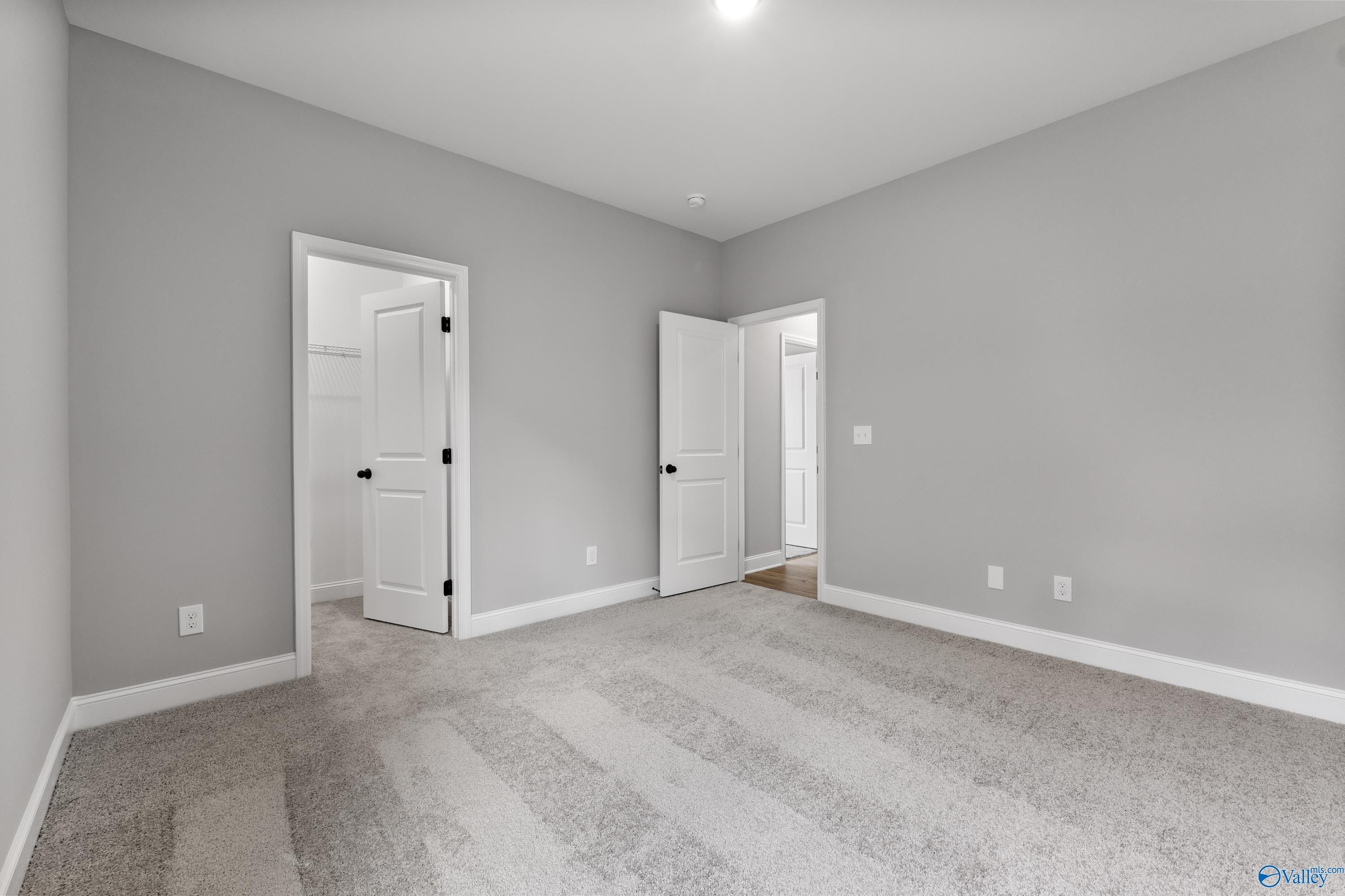 Spacious gray bedroom with open closet doors and plush carpet in Davidson Homes The Montgomery B With Bonus, Toney, AL