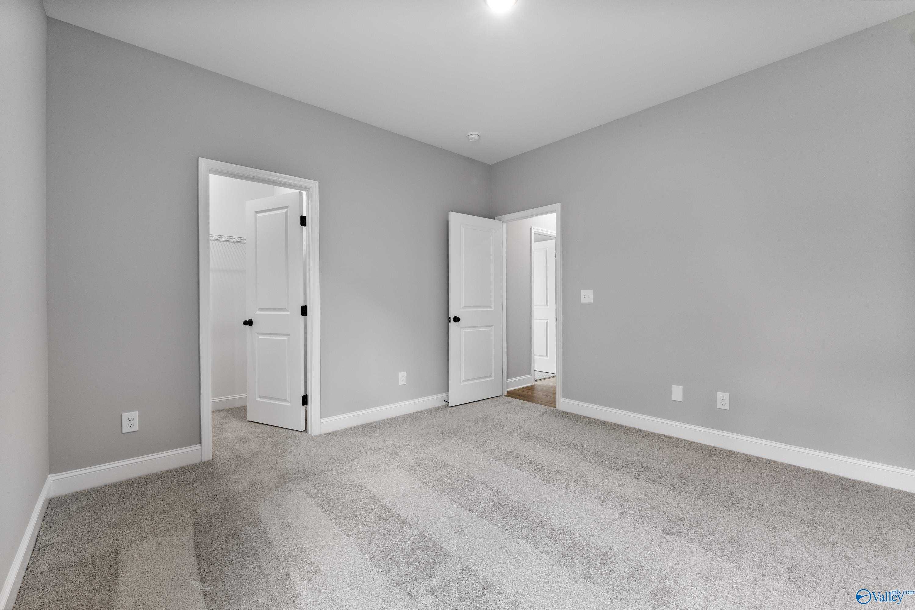 Spacious gray bedroom with open closet doors and plush carpet in Davidson Homes The Montgomery B With Bonus, Toney, AL