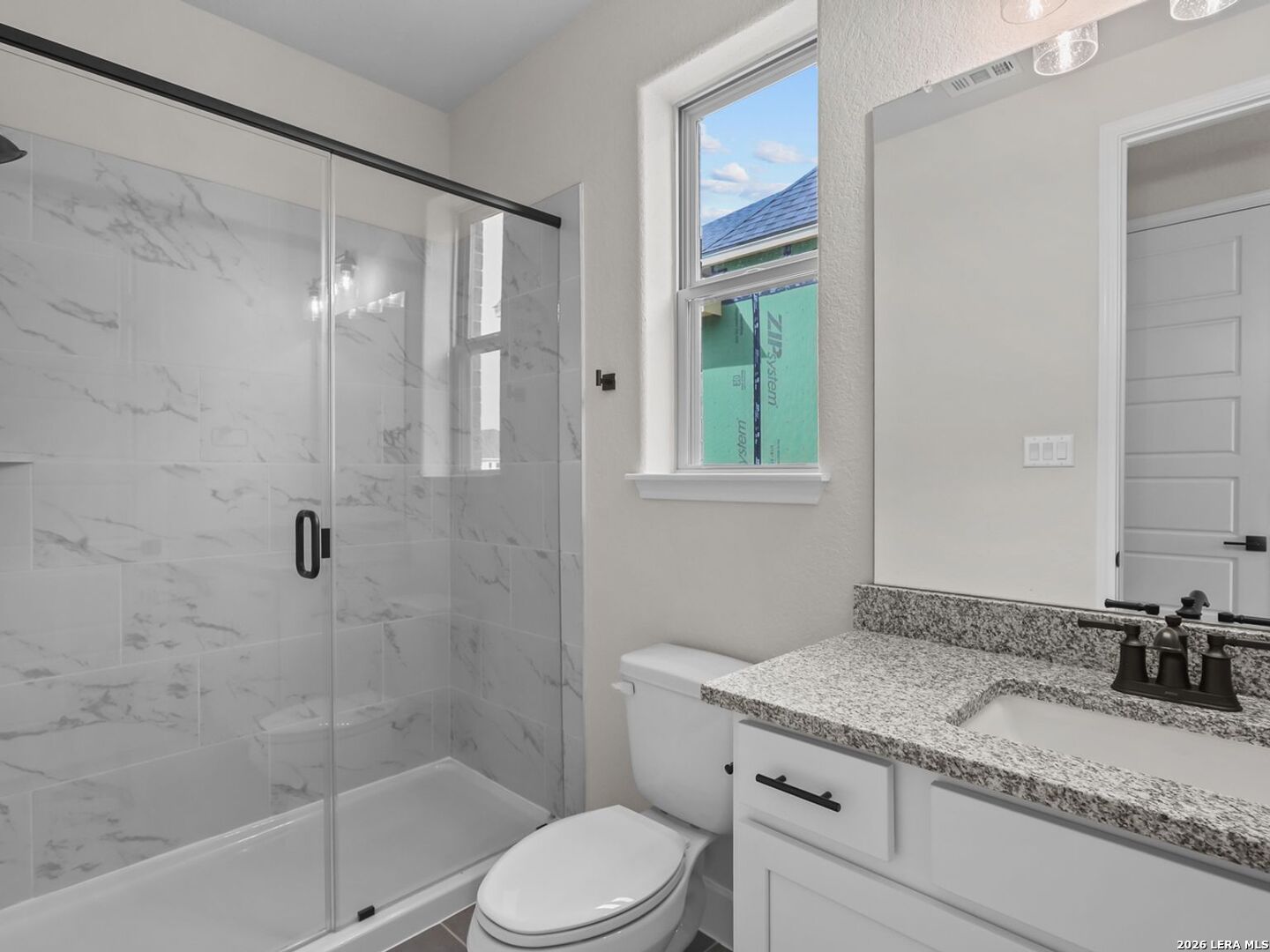 Modern bathroom with marble-tiled walk-in shower and granite vanity in Davidson Homes Belmont floor plan, Castroville, TX.
