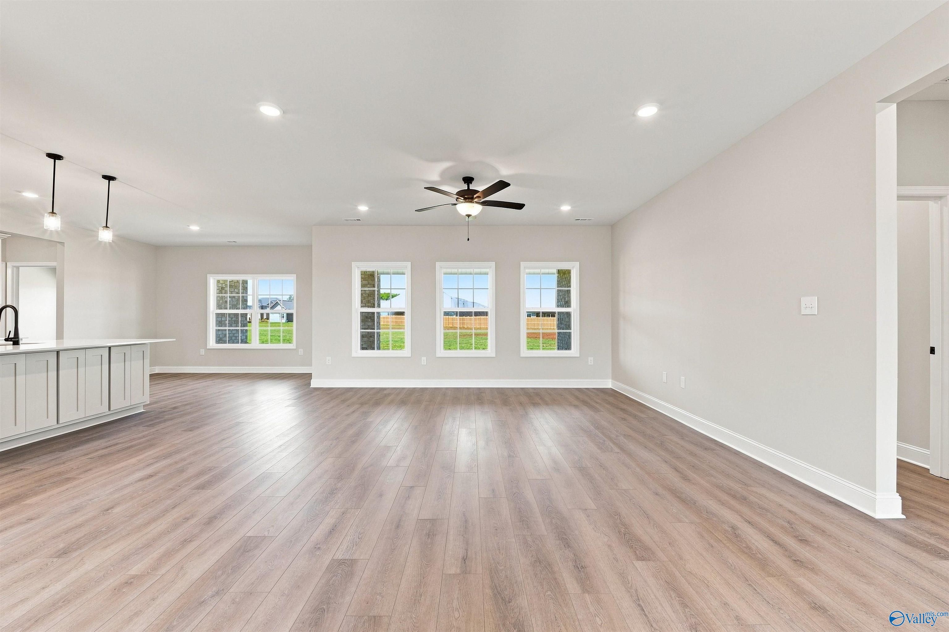 Spacious open-concept living area with wood-look flooring in The Oxford floor plan at Kendall Farms in Toney, Alabama.