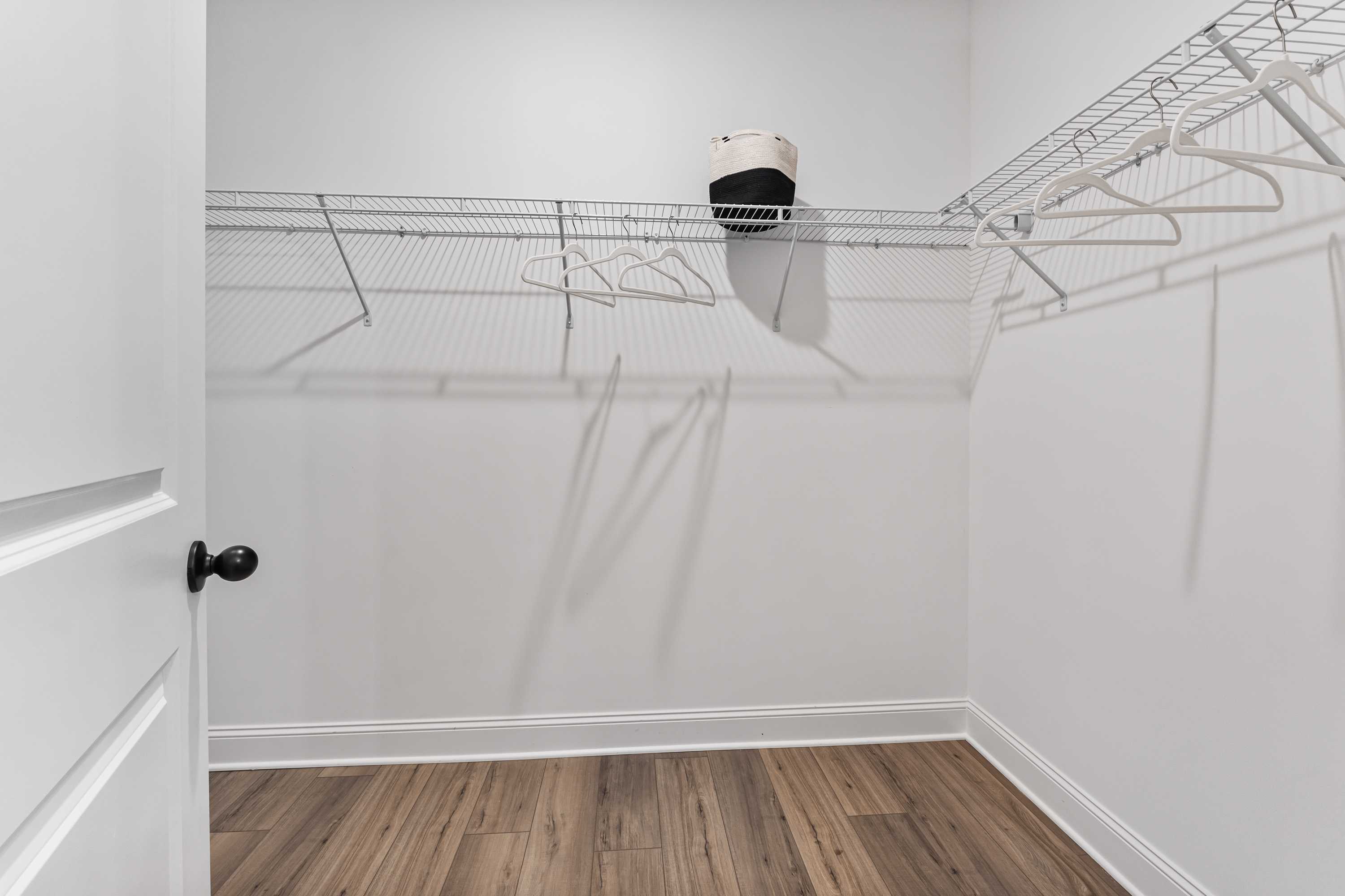 Spacious walk-in closet in Lynn Meadows Meridianville Alabama with wire shelving hangers storage basket and hardwood floors