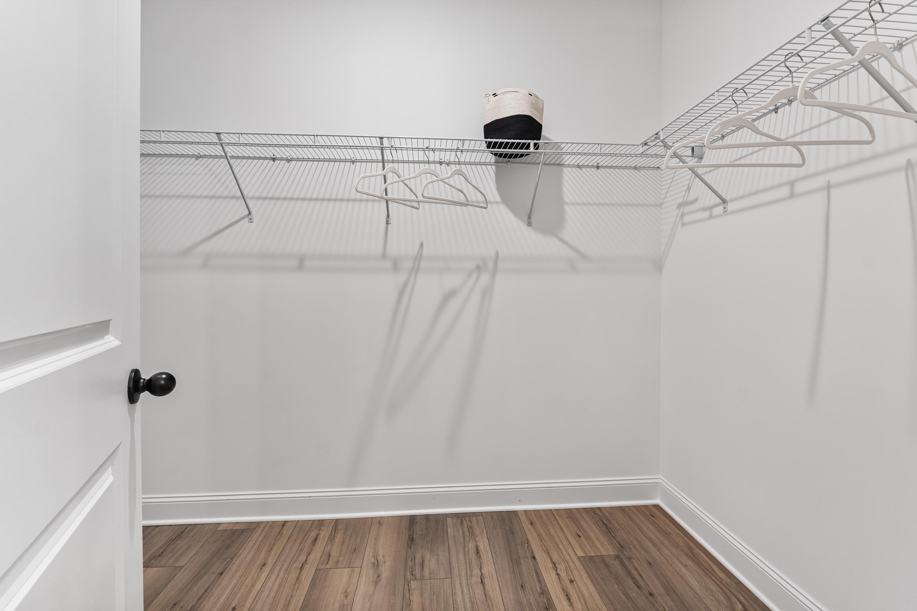 Spacious walk-in closet in Lynn Meadows Meridianville Alabama with wire shelving hangers storage basket and hardwood floors