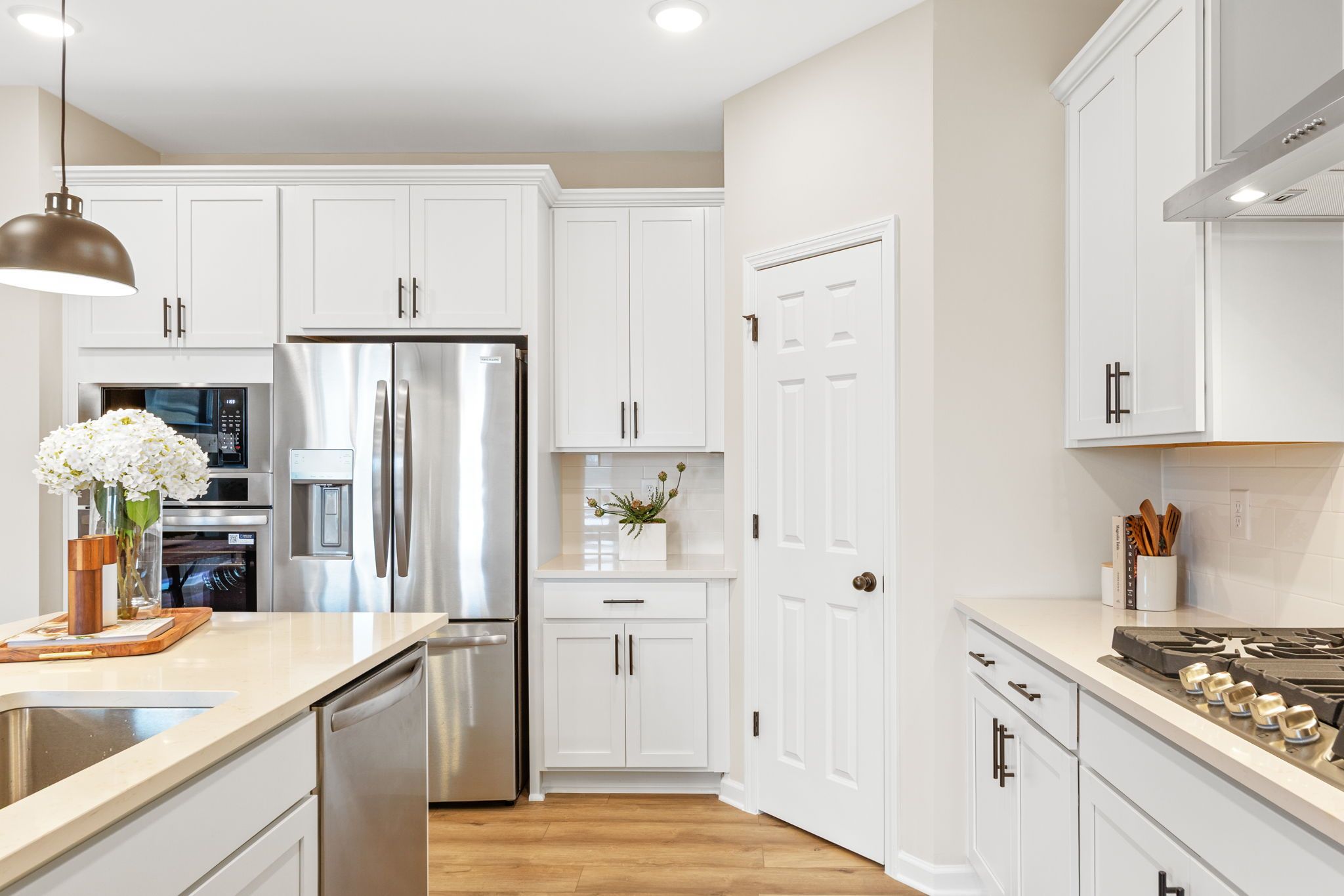 Modern kitchen in Hemingway, Cumming GA with white shaker cabinets, quartz countertops, stainless steel appliances, and hardwood floors