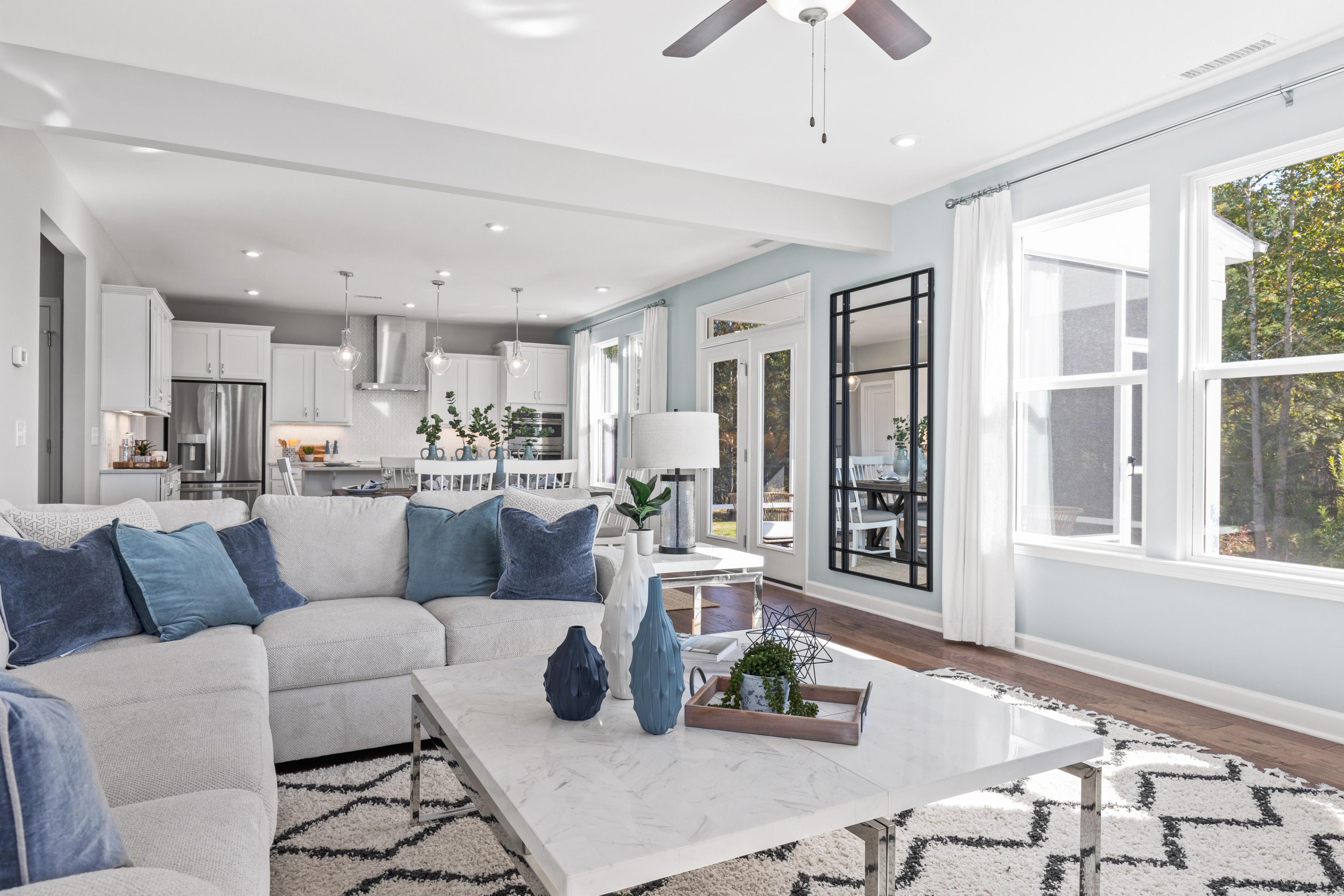 Spacious open-concept living room and kitchen at Enclave at Belmont in Belmont NC with blue sectional sofa, hardwood floors, and large windows