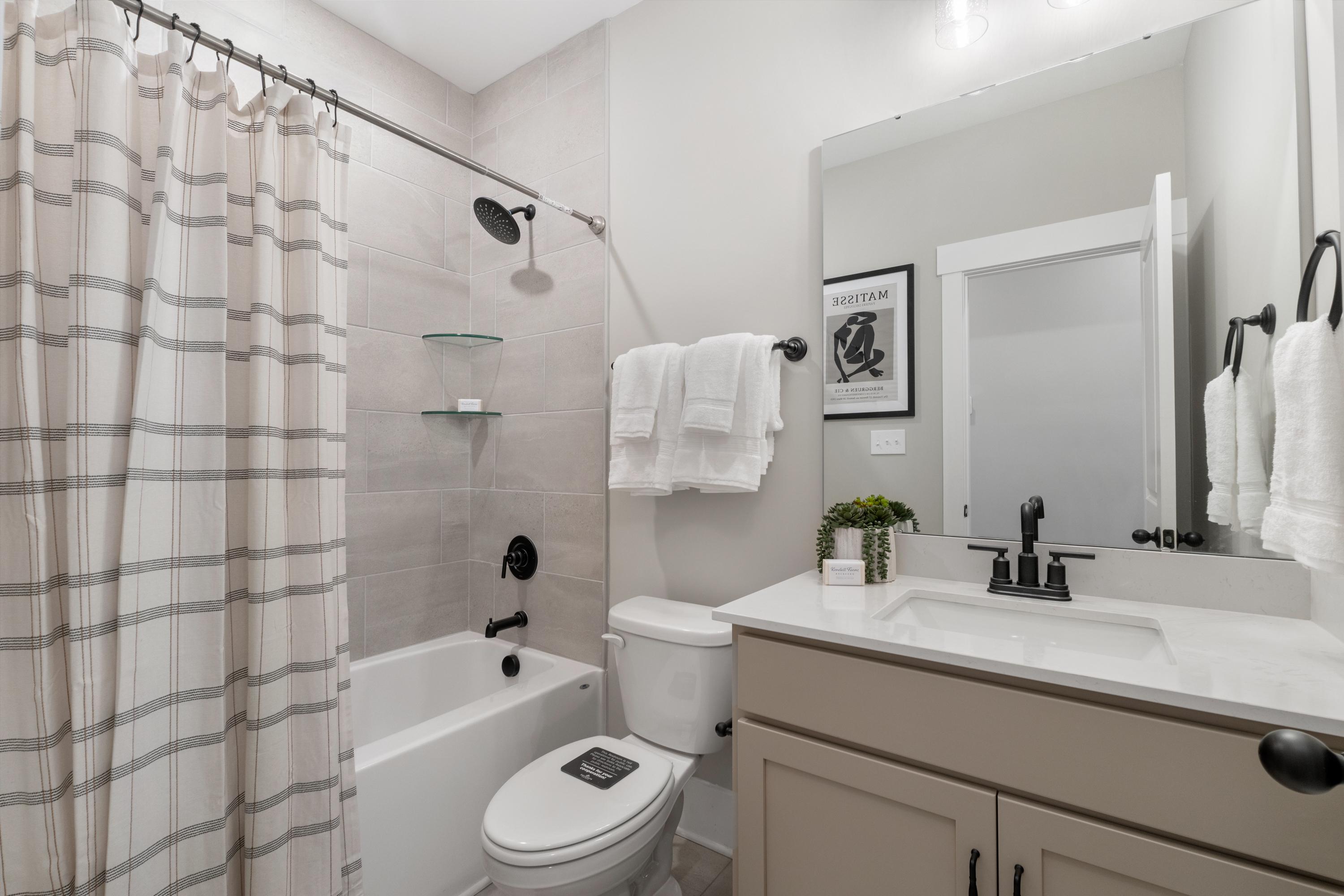 Modern bathroom in Little Creek Arab Alabama with striped shower curtain soaking tub and neutral vanity