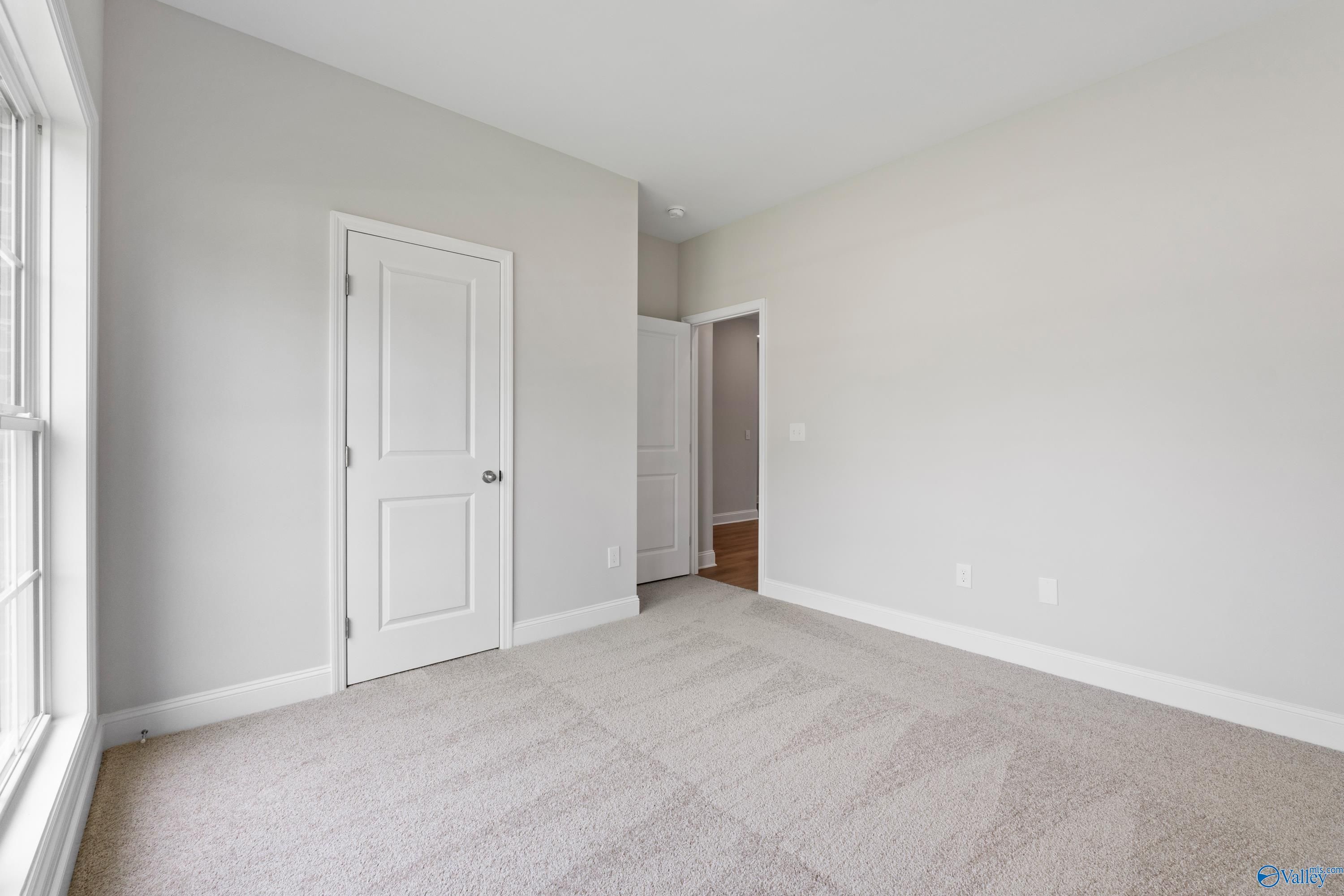 Spacious secondary bedroom with gray walls, beige carpet, large window and doors in Davidson Homes The Franklin C, Harvest AL