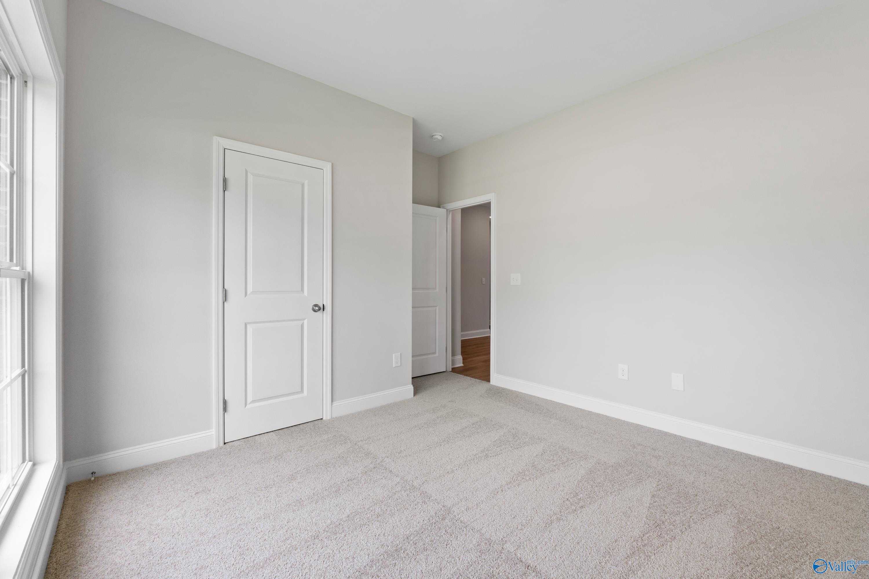 Spacious secondary bedroom with gray walls, beige carpet, large window and doors in Davidson Homes The Franklin C, Harvest AL