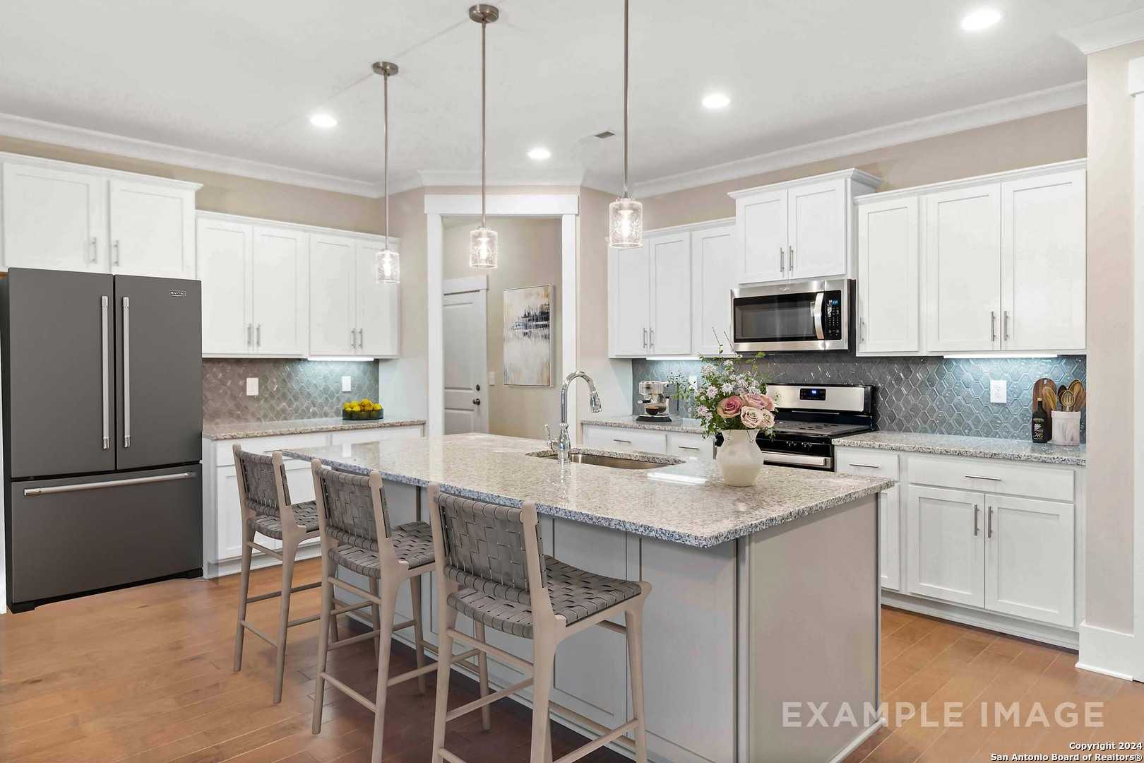 Modern white kitchen with granite island, stainless appliances, pendant lights in The Lanier H by Davidson Homes, Ladera, San Antonio