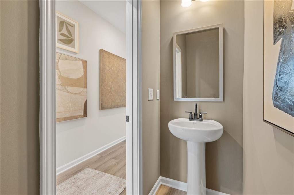 Half bath with pedestal sink and modern wall art in The Rabun B floor plan at The Bluffs, Canton, Georgia.