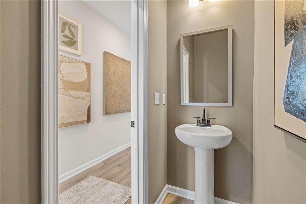 Half bath with pedestal sink and modern wall art in The Rabun B floor plan at The Bluffs, Canton, Georgia.