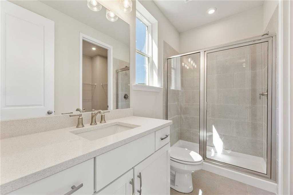 Modern bathroom with quartz vanity, white cabinets, frameless glass shower in The Danbury E by Davidson Homes, Buford, Georgia