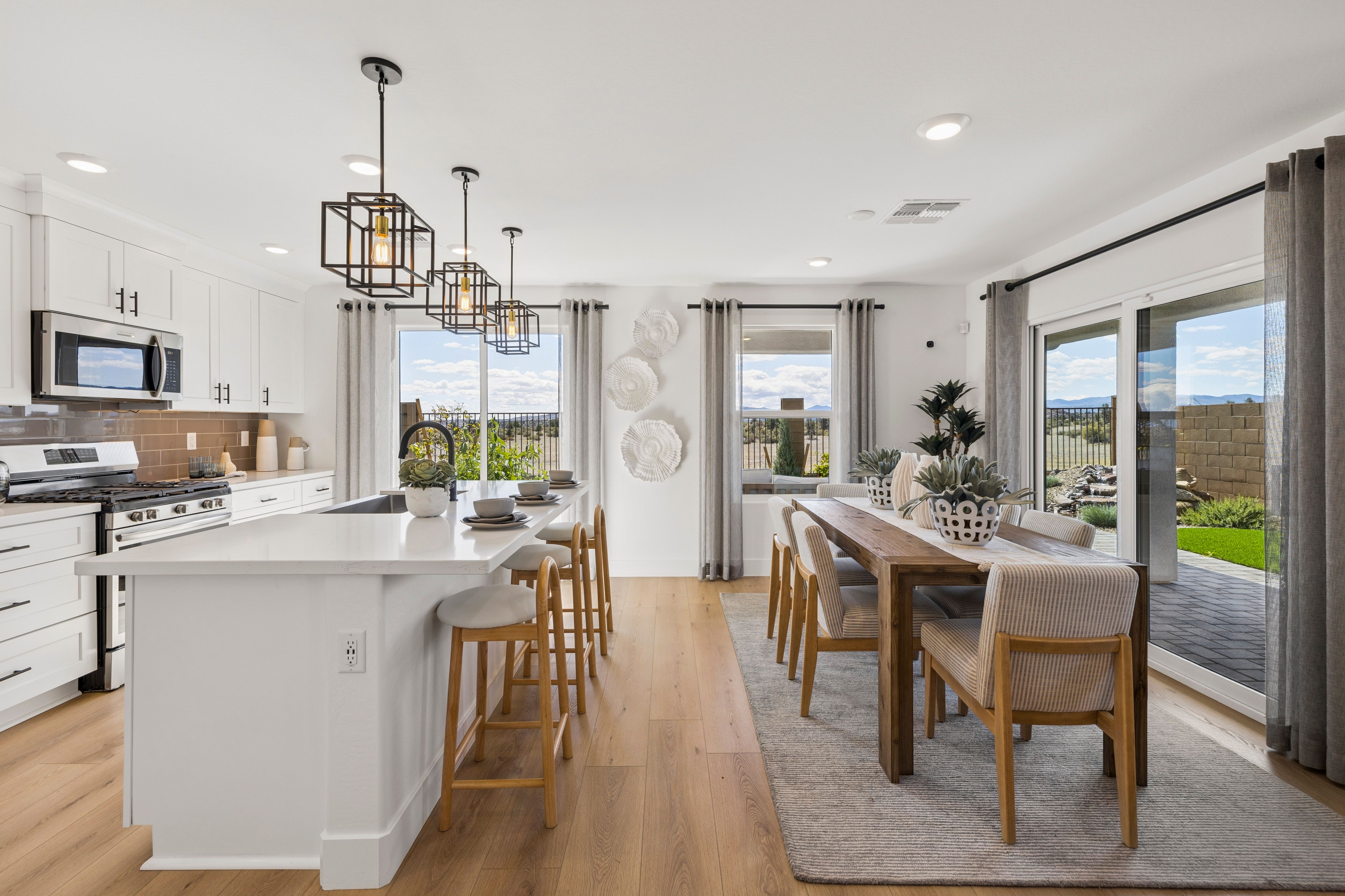 Spacious modern kitchen in South Ranch Southern Collection Prescott AZ with white quartz island, stainless appliances, pendant lighting and desert views