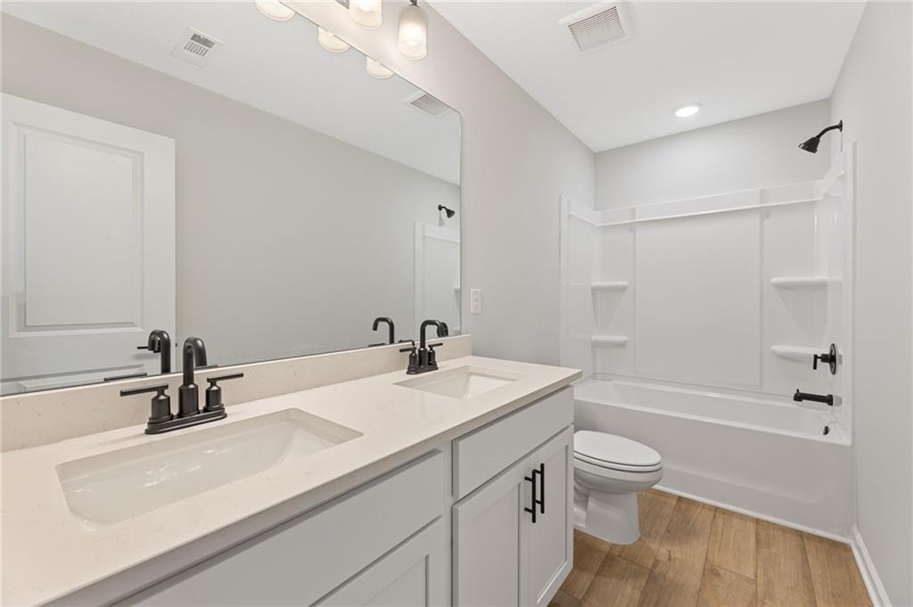Modern master bathroom with double vanity, soaking tub, glass shower, and wood floors in Davidson Homes The Rabun C, Winder, Georgia