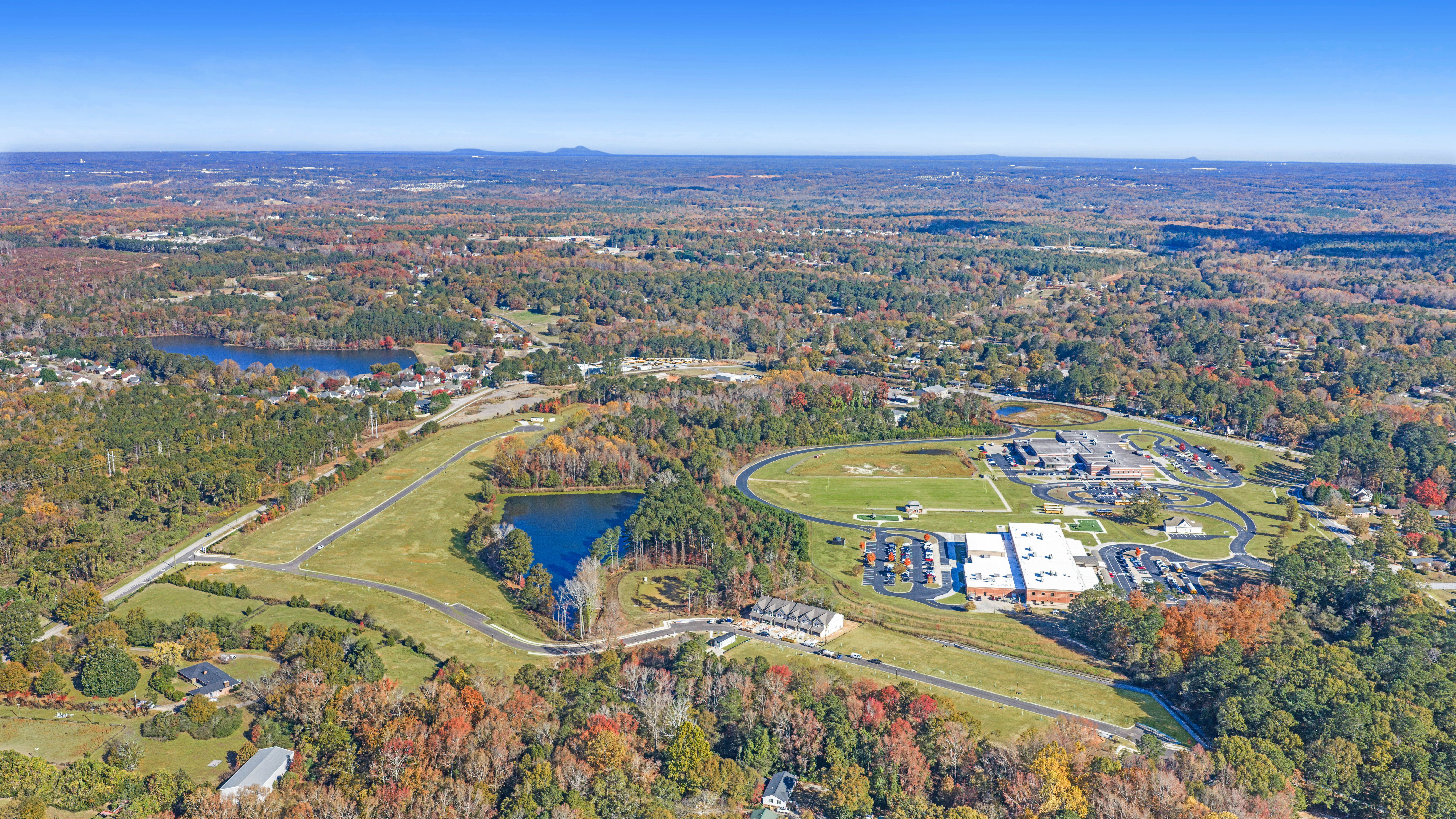 Aerial view of Lake Shore community in Winder GA featuring resort-style pool, clubhouse, lush forest, and serene lakefront