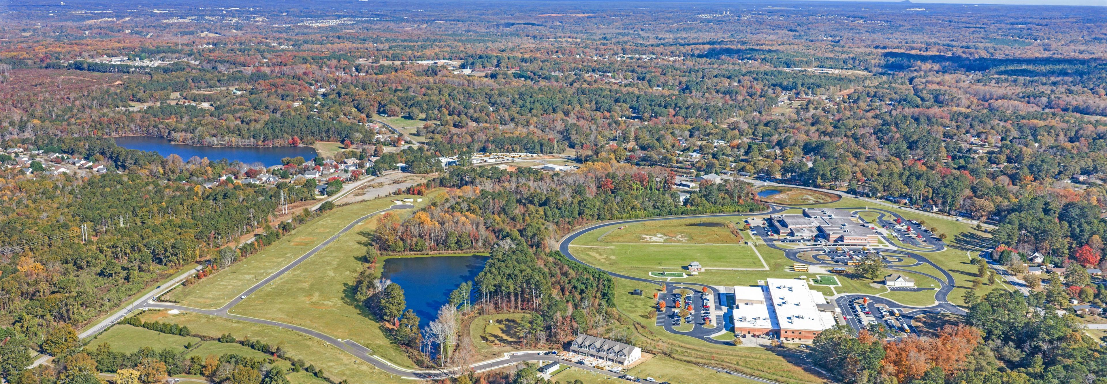 Aerial view of Lake Shore community in Winder GA featuring resort-style pool, clubhouse, lush forest, and serene lakefront