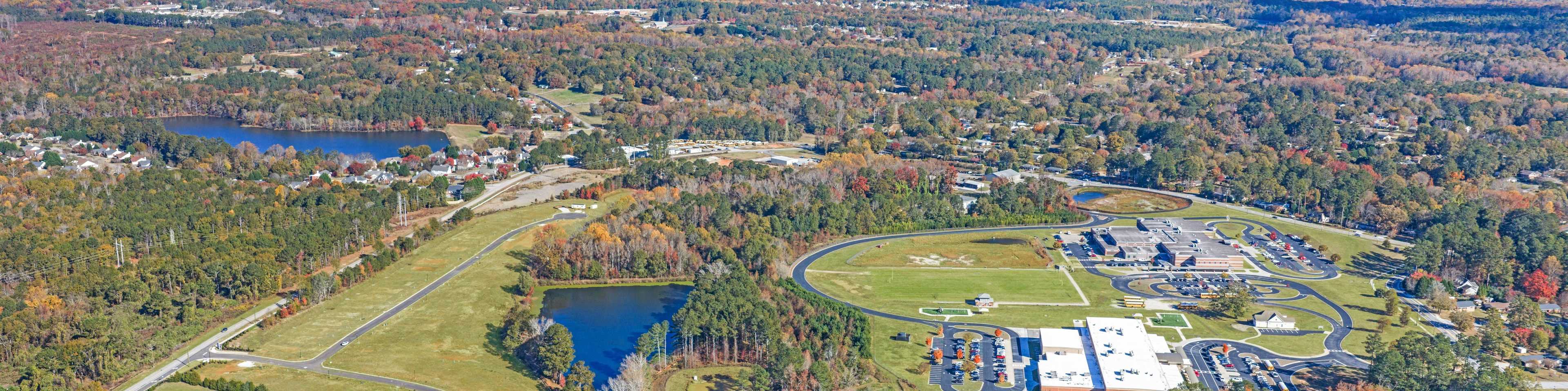 Aerial view of Lake Shore community in Winder GA featuring resort-style pool, clubhouse, lush forest, and serene lakefront