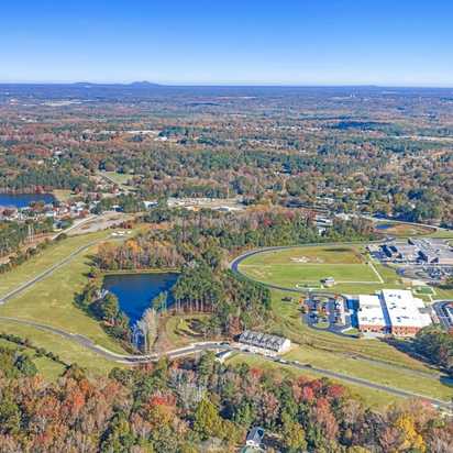 Aerial view of Lake Shore community in Winder GA featuring resort-style pool, clubhouse, lush forest, and serene lakefront
